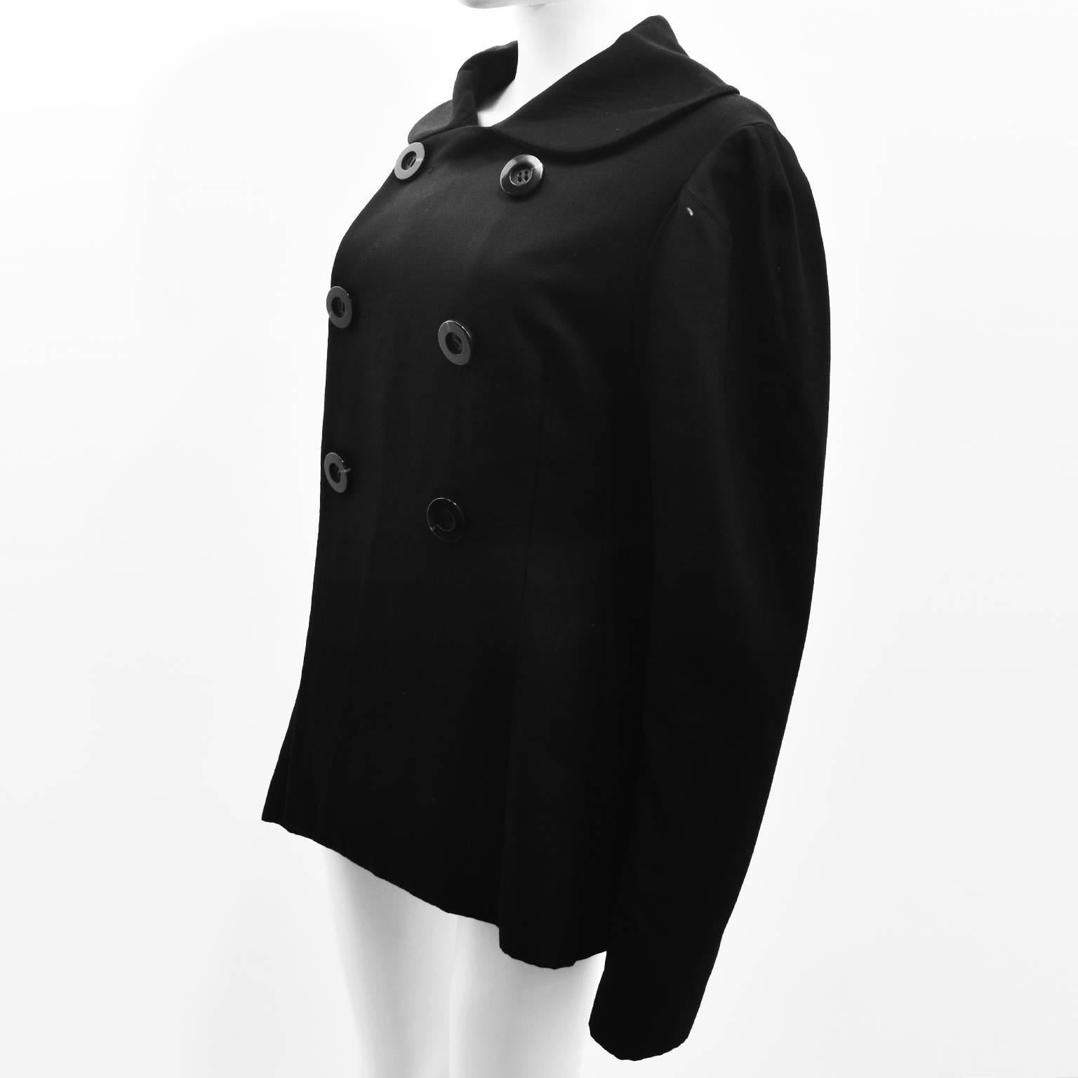 A black jacket by Yohji Yamamoto with interesting design details. The jacket is double breasted with a boxy shape and a large round collar. It also features large, oversized sleeves that puff slightly at the shoulder creating an unusual silhouette.