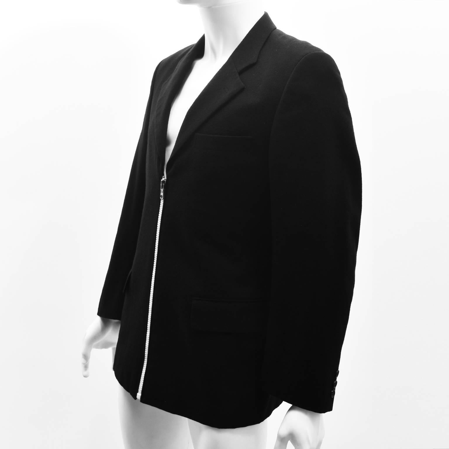 A classic black blazer with a twist from Comme des Garcons’ Homme line. The blazer has a simple, straight cut with notched collar and pockets at the hip. It also features a central chunky zip in a contrast white colour creating a contemporary and