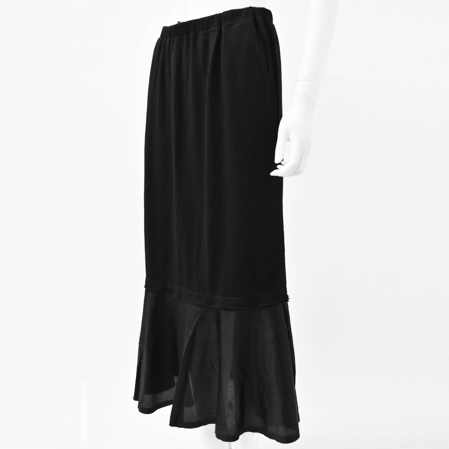 A classic and versatile black long skirt from Comme des Garcons. The skirt has a long, straight silhouette with a slight flare in the bottom where there is the contrasting panel of material. It has an elasticated waist and is a Japanese size Medium