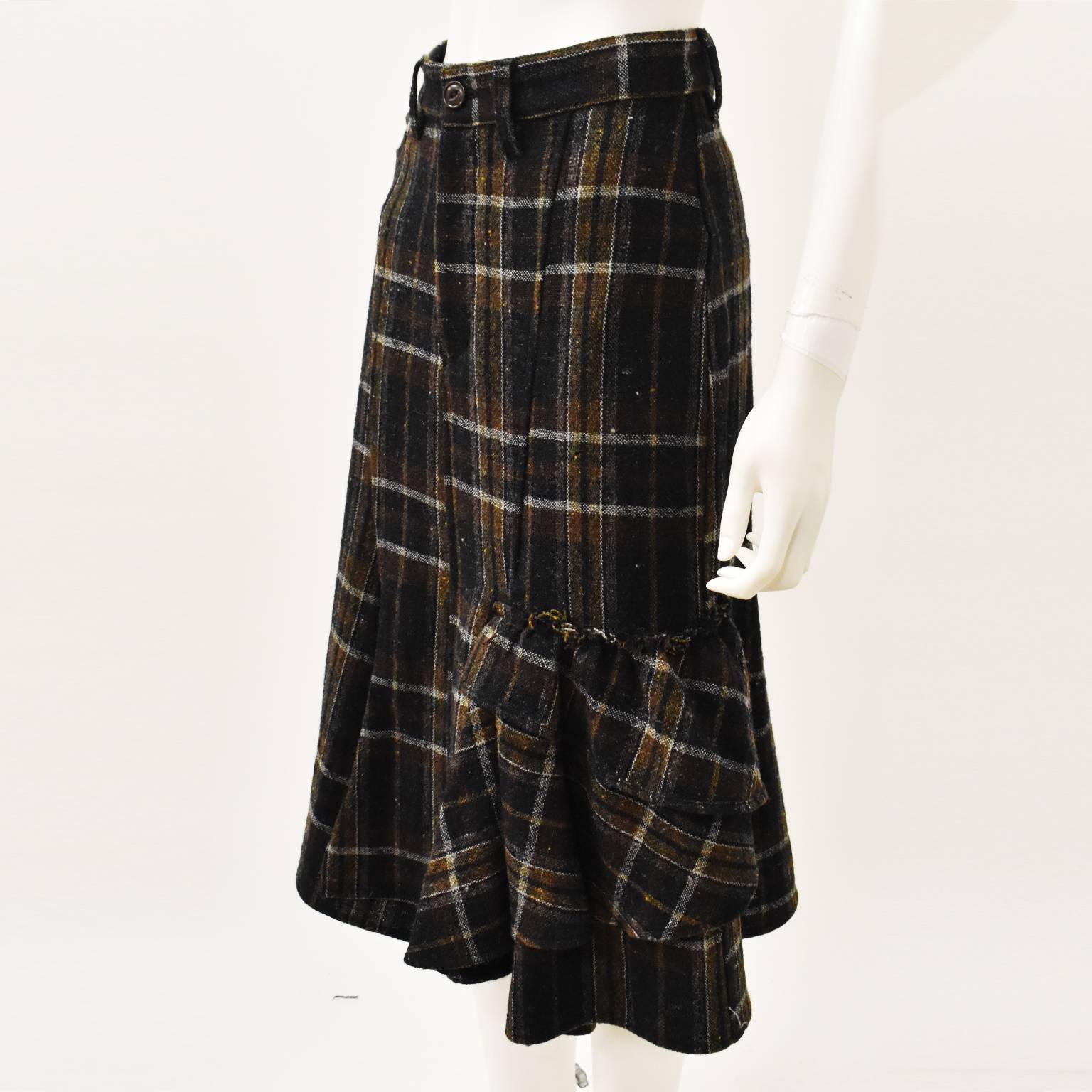 A Japanese twist on a classic check skirt from Yohji Yamamoto’s Y’s label. The skirt has a simple,  A-line shape but has a deconstructed ruffles on one side. The skirt sits on the waist and has a central button and zip fastening. It is made from a