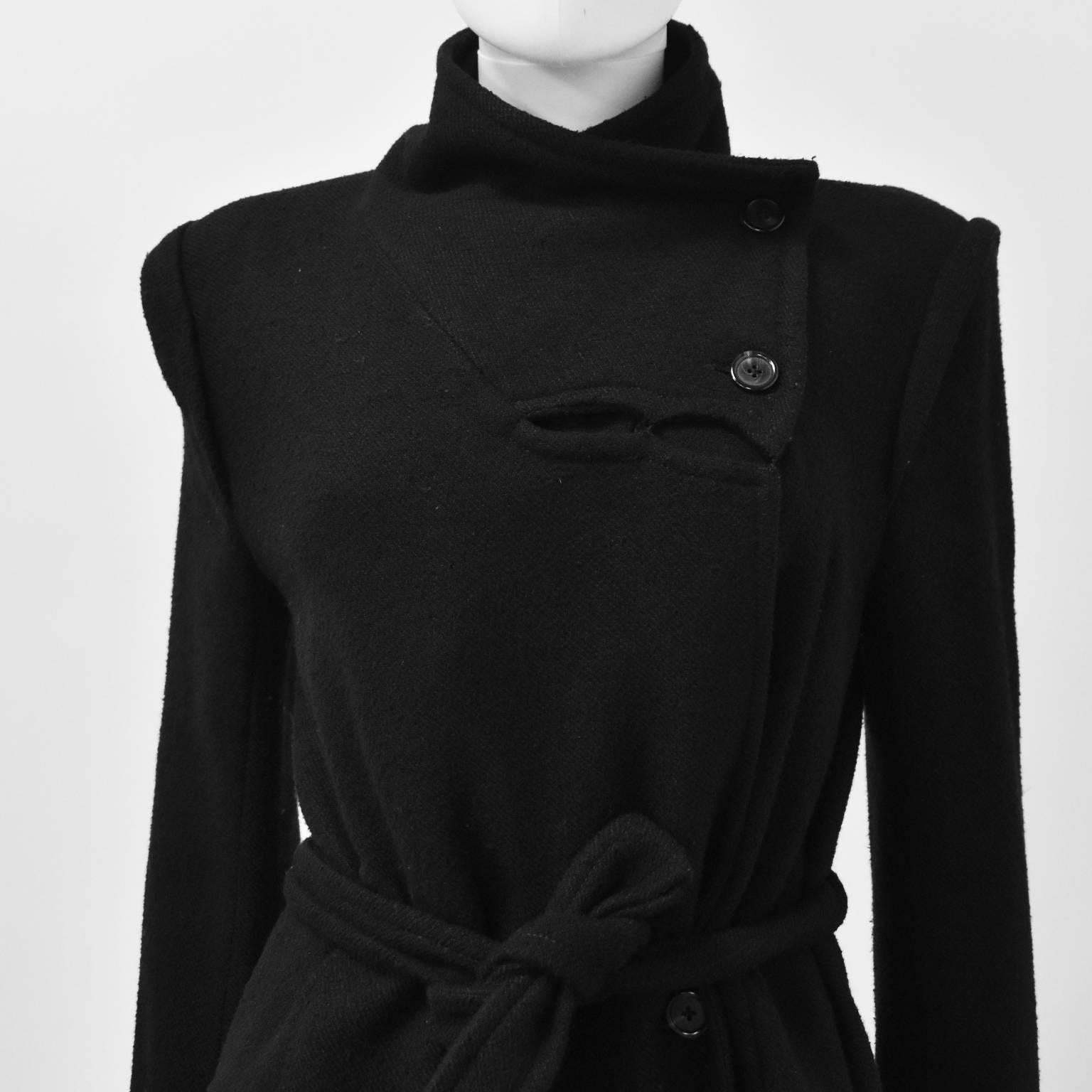 A beautiful Winter coat by Belgian designer Ann Demeulemeester. The coat has a military-esque design with an asymmetric collar and button fastening that can be worn open to create a one-sided collar or a funnel neck. The coat has a diagonal