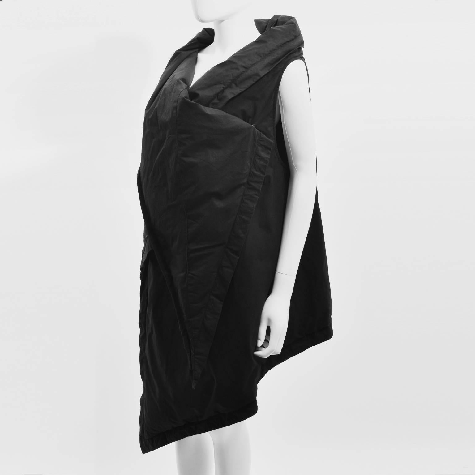 A black cotton goose down padded gilet from Rick Owens. The gilet has an unusual geometric shape that when wrapped around the body creates an exaggerated pointed collar and long point that falls down the front of the body. It is made from a soft,