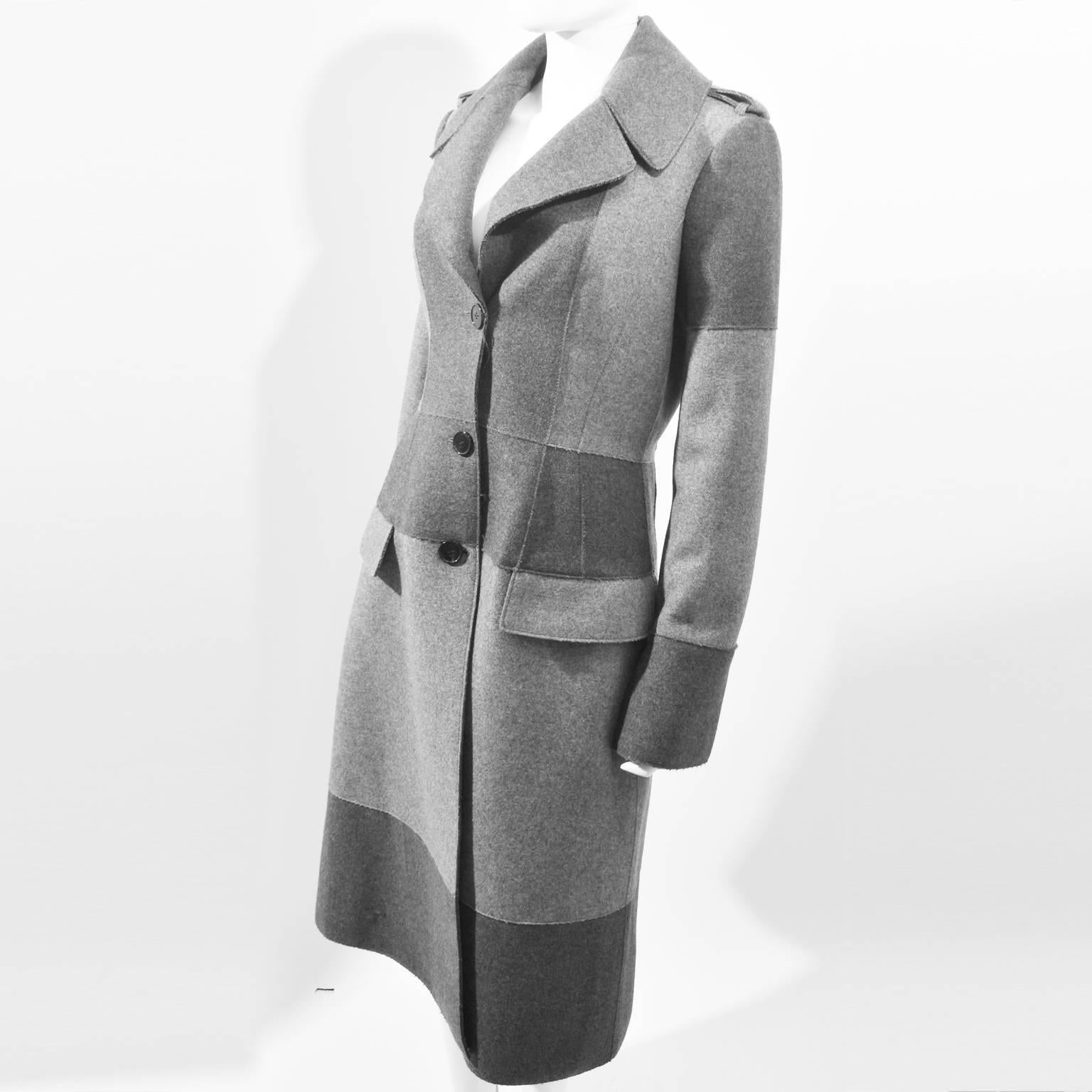 A beautiful and luxurious wool coat by Alexander McQueen. The coat has a large collar, and a slim fitted shape with a button-up fastening, epaulettes and two pockets at the hip. The coat is made from two tones of grey wool that are stitched together
