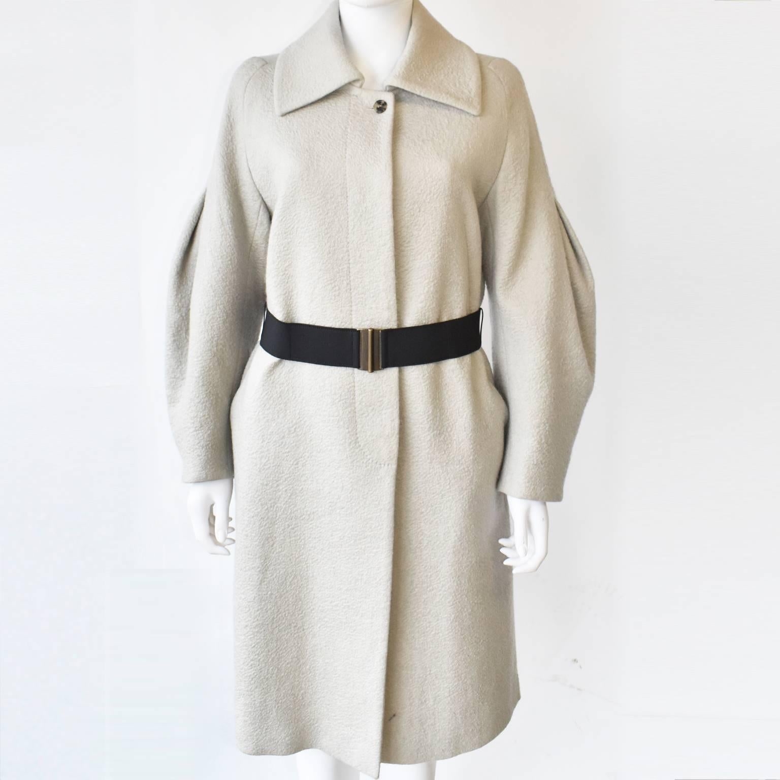 A light sand coloured textured wool blend coat with balloon sleeves by Dries Van Noten. It features a large collar,  button fastening, and a black elasticated belt but can be worn without. It is in excellent condition. 