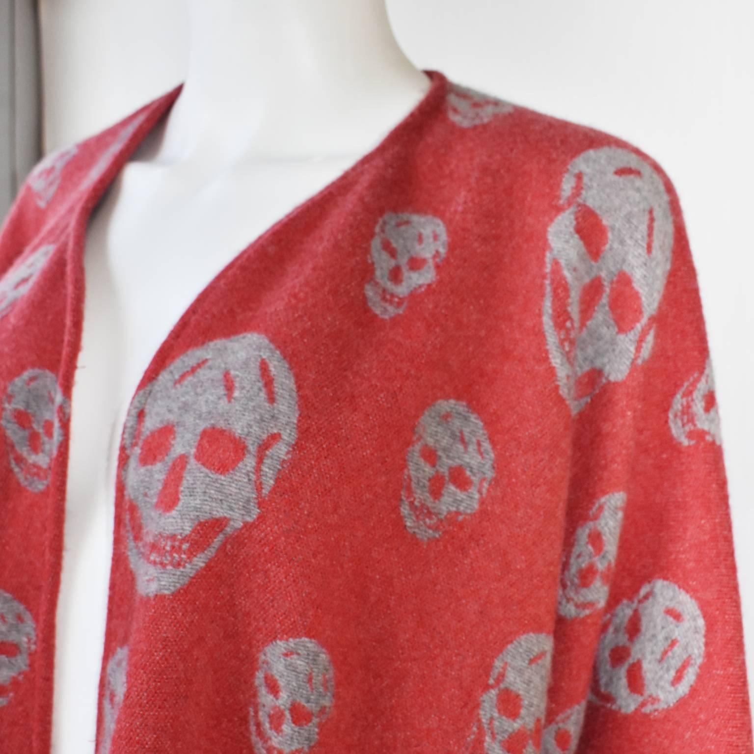 A red cape with fringes and grey skull motifs by Alexander McQueen. The item is brand new. It has no fastening and can be styled in a variety of ways. Free size.
