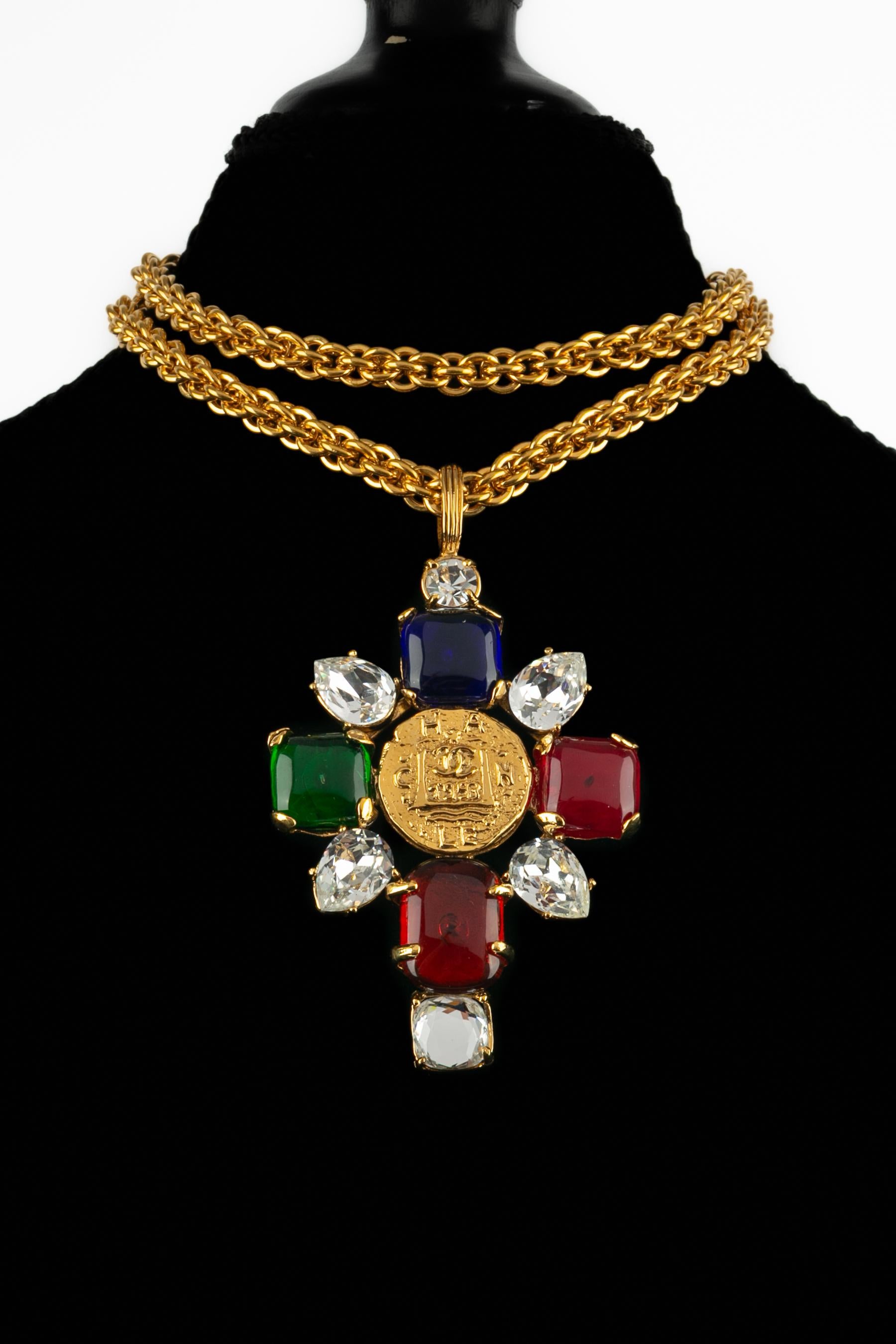 CHANEL - (Fabriqué en France) Long collier pendentif représentant une croix ornée de cabochons en pâte de verre et d'un strass. Collectional automne-hiver 1993 sous la direction artistique de Karl Lagerfeld.

Condit :
Très bon état.

Dimensions