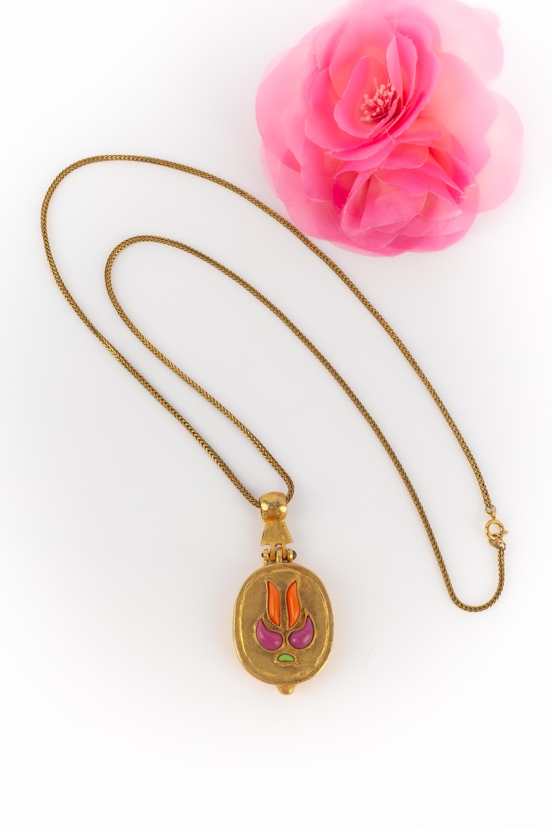 GUERLAIN - Collana a catena in metallo dorato con un ciondolo a forma di scatola in metallo dorato battuto e decorato con resina colorata. Specchio interno. Gioielli creati dalla Maison Goossens per Guerlain.

Condizioni:
Ottime