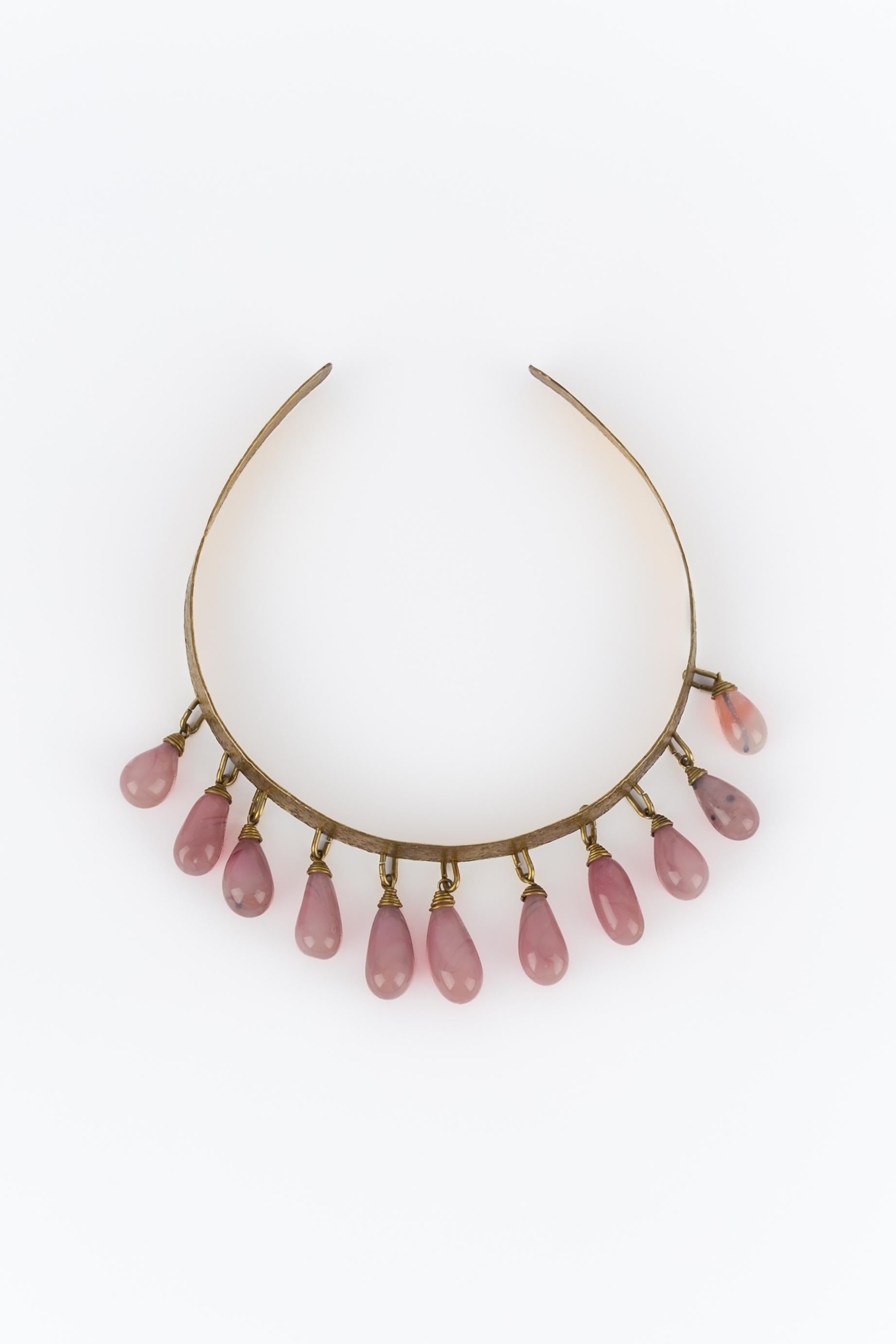 UNBEKANNT - Kurze, geschlagene goldene Metallkette mit rosa Glastropfen. Unsignierter Schmuck aus den 1920er Jahren. Er kann als Kopfschmuck getragen werden.

Bedingung:
Sehr guter Zustand

Abmessungen:
Umfang: 33 cm - Öffnung: 5,5 cm

SKU:BC214