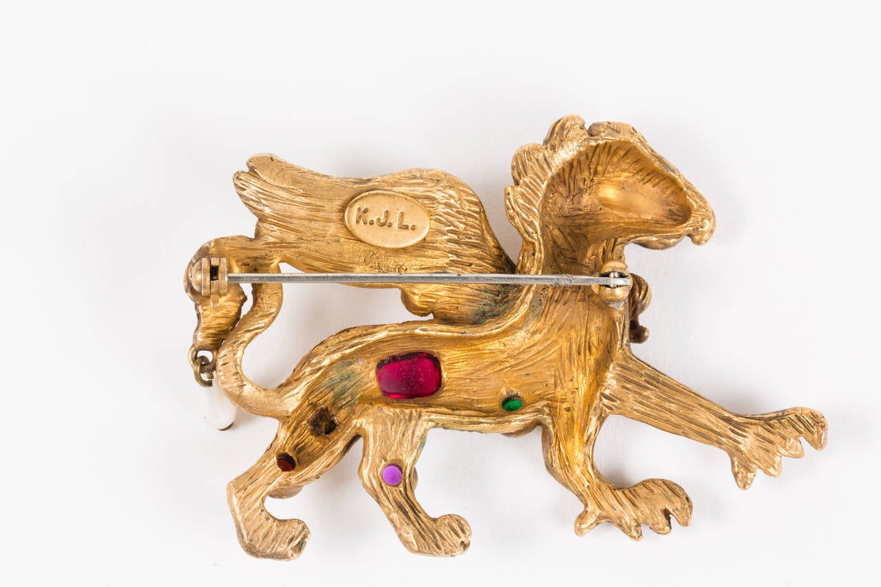 Striking stylized griffin brooch in aged gilt brass inset with glass stones and rhinestones. Truly a little jewel of a piece, the tail is accented by a single teardrop shaped pearl. In antiquity the griffin was considered a symbol of divine power