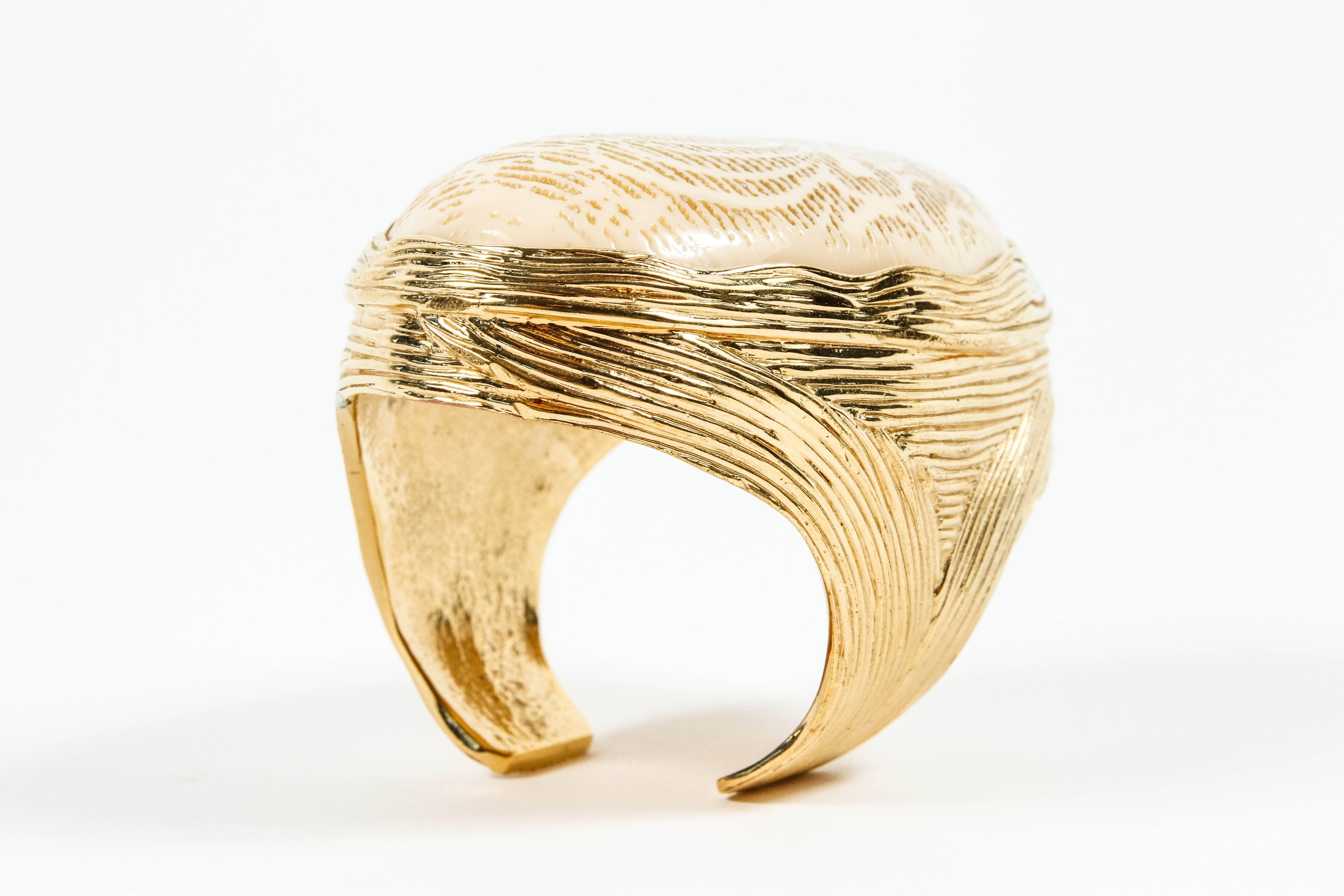 A really striking cuff featuring a faux ivory oval with a stylized scarab engraved on the surface nestled in a gilt gold setting resembling wire work.  I am not certain but this looks as though it could be the work of master jeweler Robert Goossens