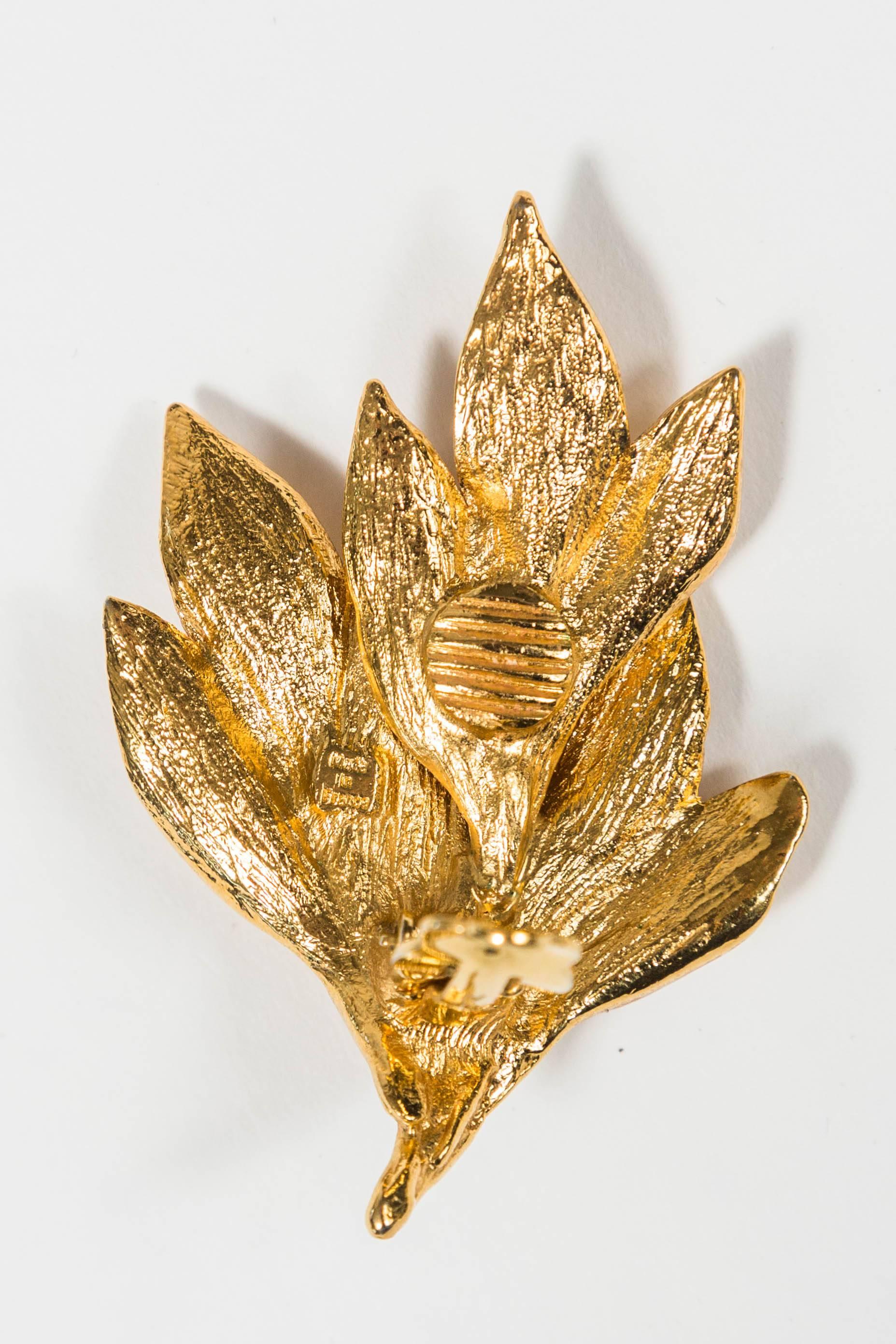 Pair of costume ear clips by French designer Yves Saint Laurent. With layered floral decoration. Solid Gilt Metal. Marked YSL and 'Made in France' on the reverse. See images 2 and 3.