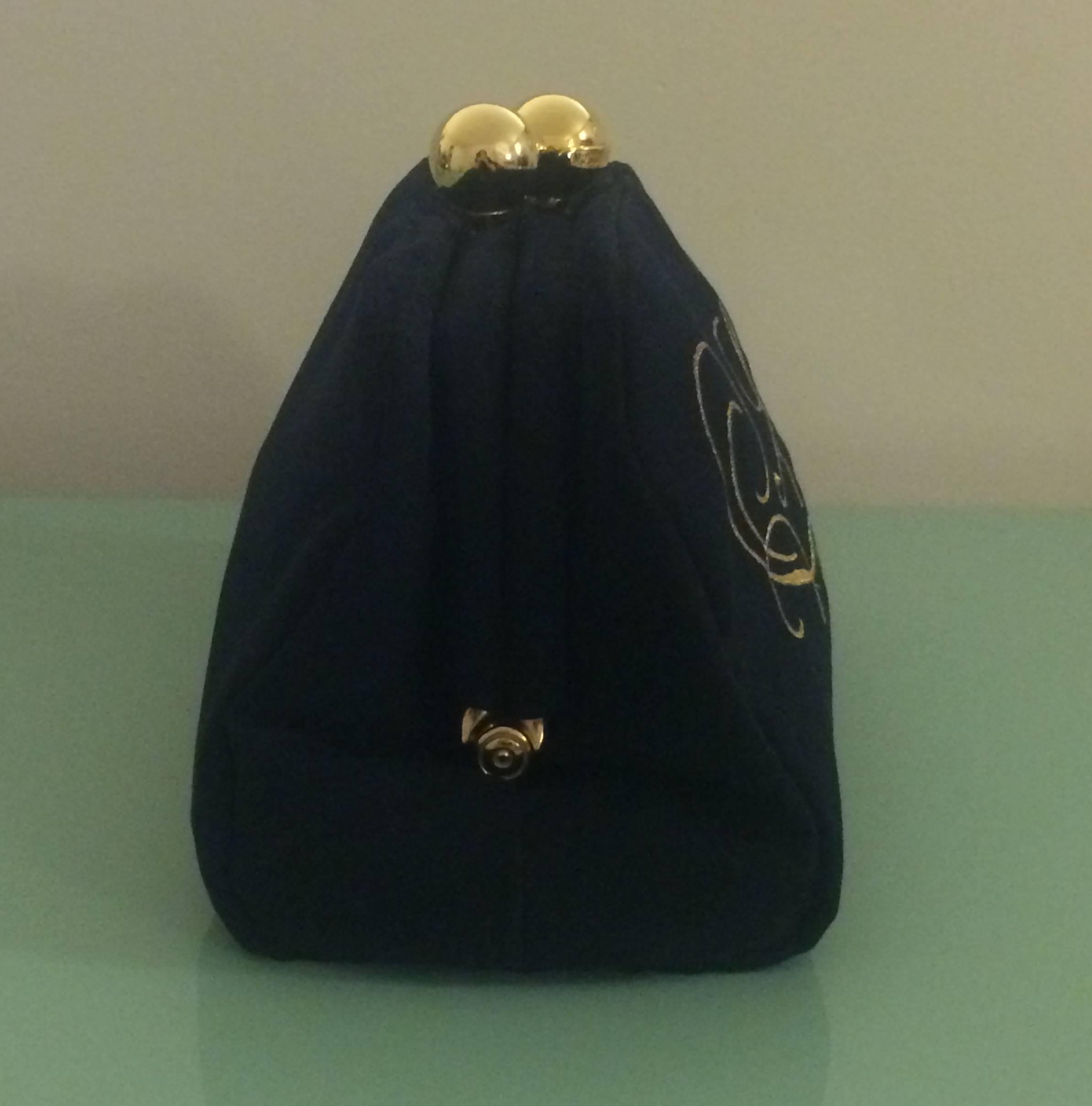 Moschino Redwall 1990's super-soft black clutch reads 'Soft!' in curling gold embroidery. Signed 'Moschino at gold ball on top.' Hinge closure (kisslock at top is decorative.)

Large main compartment and small interior zippered pocket.

Made in