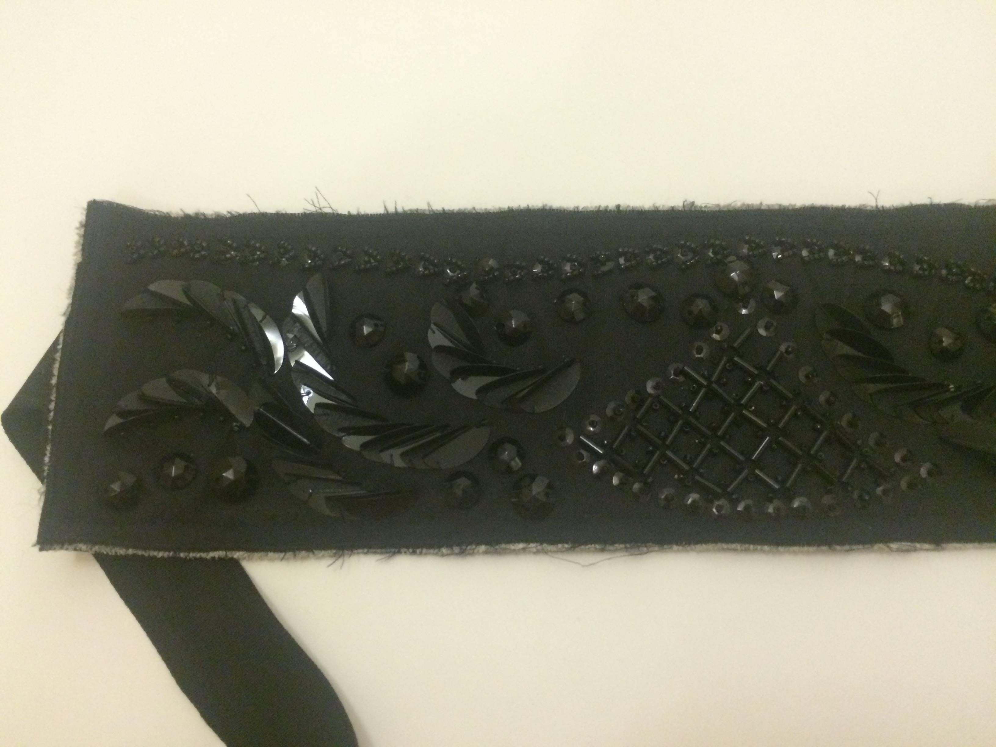 Prada black cloth belt embellished by beadwork. Raw edges with bits of the cream interior exposed. Black moire grosgrain ribbon closure.

Made in Italy. 

One size fits all.
Panel measures 19 1/4
