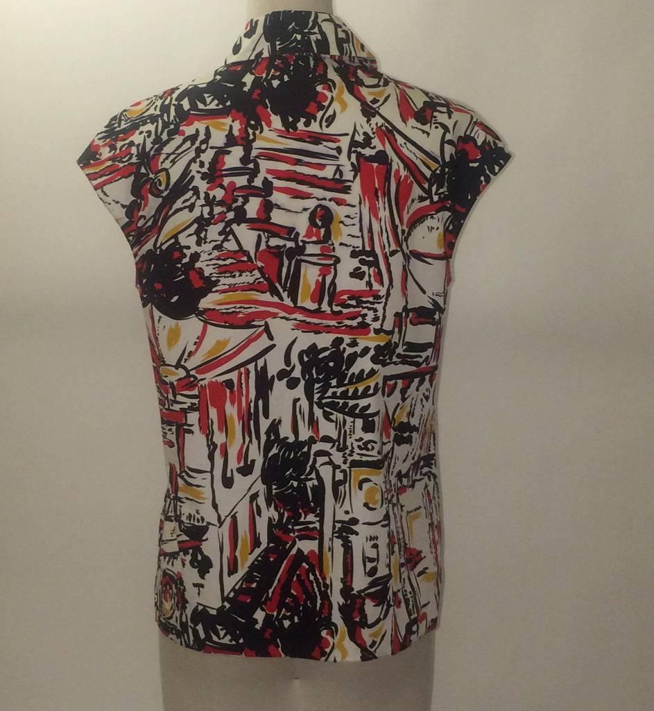 Prada 2014 red and yellow blouse with Italian city print. Button front. Slightly  boxy fit-- we love it tied at the waist with a dark skinny jean or full black skirt. 

100% cotton.

Size IT 38, approximate US 2 but runs big, see