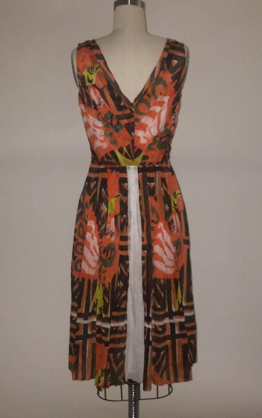 Prada orange pleated cotton dress with brown, white, green and yellow tribal print throughout. V neck at front and back. Side zip, fully lined, reinforced with grosgrain at waist and side zip.

100% cotton.

Made in Italy.

Size It 40,