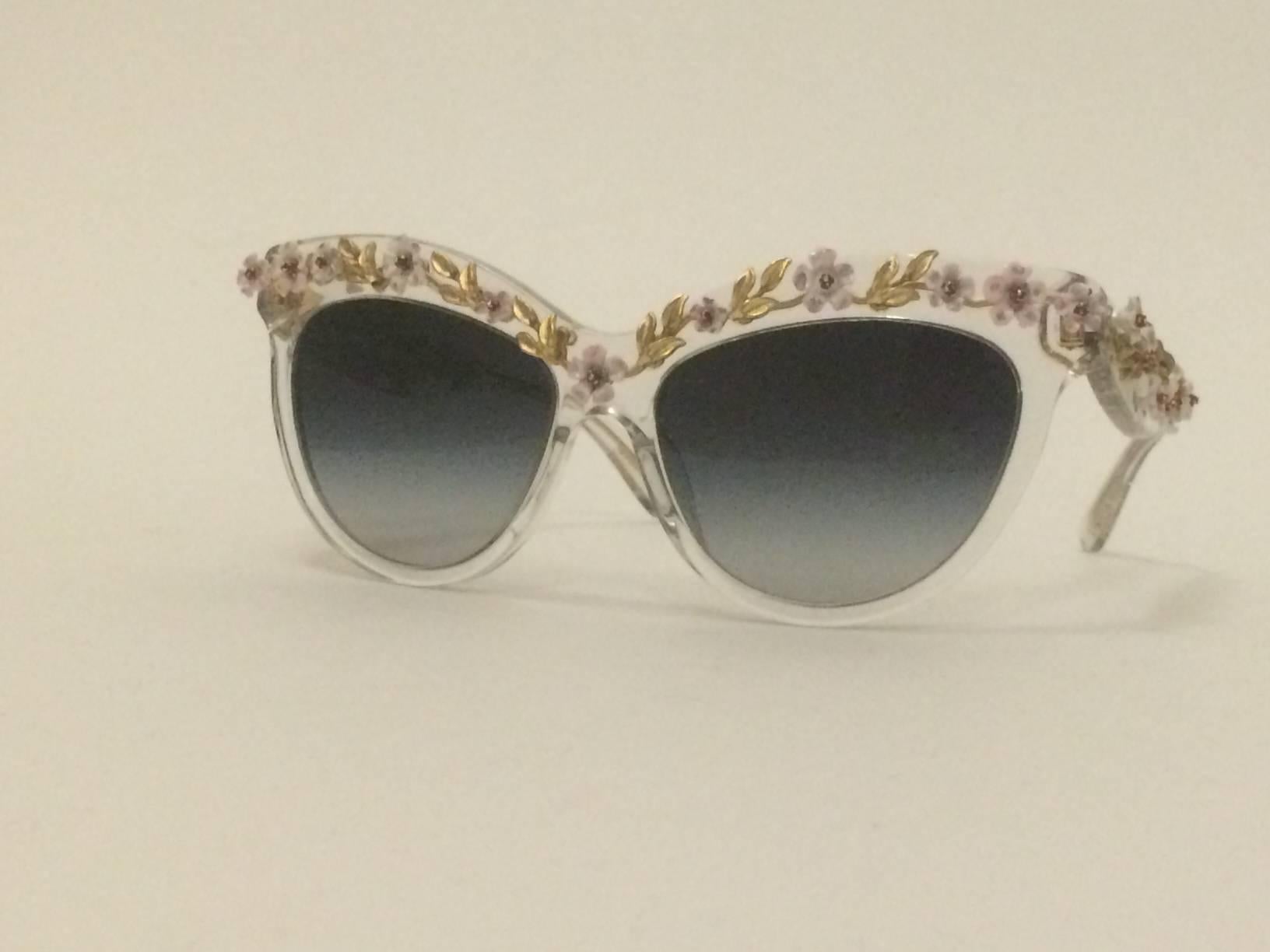Stunning Dolce & Gabbana cat eye sunglasses adorned with handprinted white, pink and lavender metal flowers. Transparent acetate frames. Grayish taupe gradient lenses. 

Very rare, produced exclusively for Luisa via Roma Boutique. Retailed at