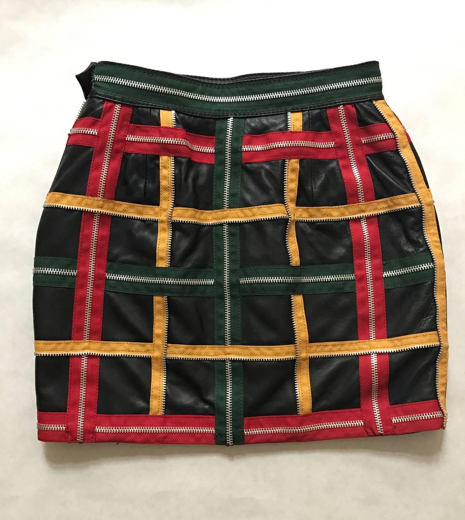 Vintage 1980's Moschino black leather mini skirt featuring yellow, green and red zippers woven into a check pattern. Iconic Franco Moschino: Biker chic meets tongue-in-cheek!  Side zip and snap.

100% leather.
Fully lined in 100% rayon.

Made
