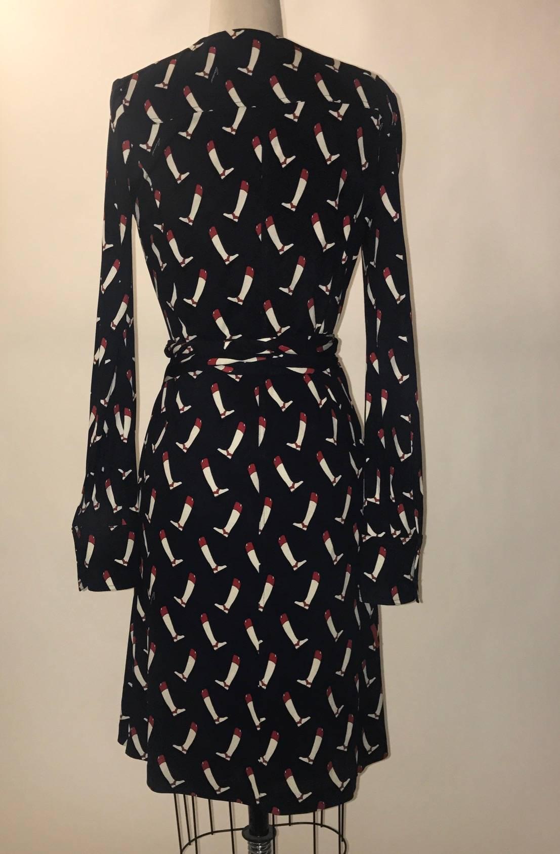 Gucci navy silk wrap dress from the 2005 collection featuring white and red equestrian boot print and white 'gucci' signature throughout. Blouse-cut sleeves with cuffs. Silver horsebit charms dangle from the ends of attached wrap belt. Closes with a