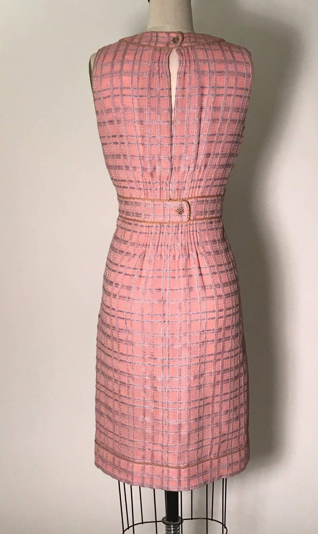 Pink and pale blue plaid sleeveless tweed dress with tan piping. Small pleat details at front. Gold CC logo buttons at back neck and waist. Slit at center back from neck to waist, fastens near middle with snap (snap may have been added.) Zip and