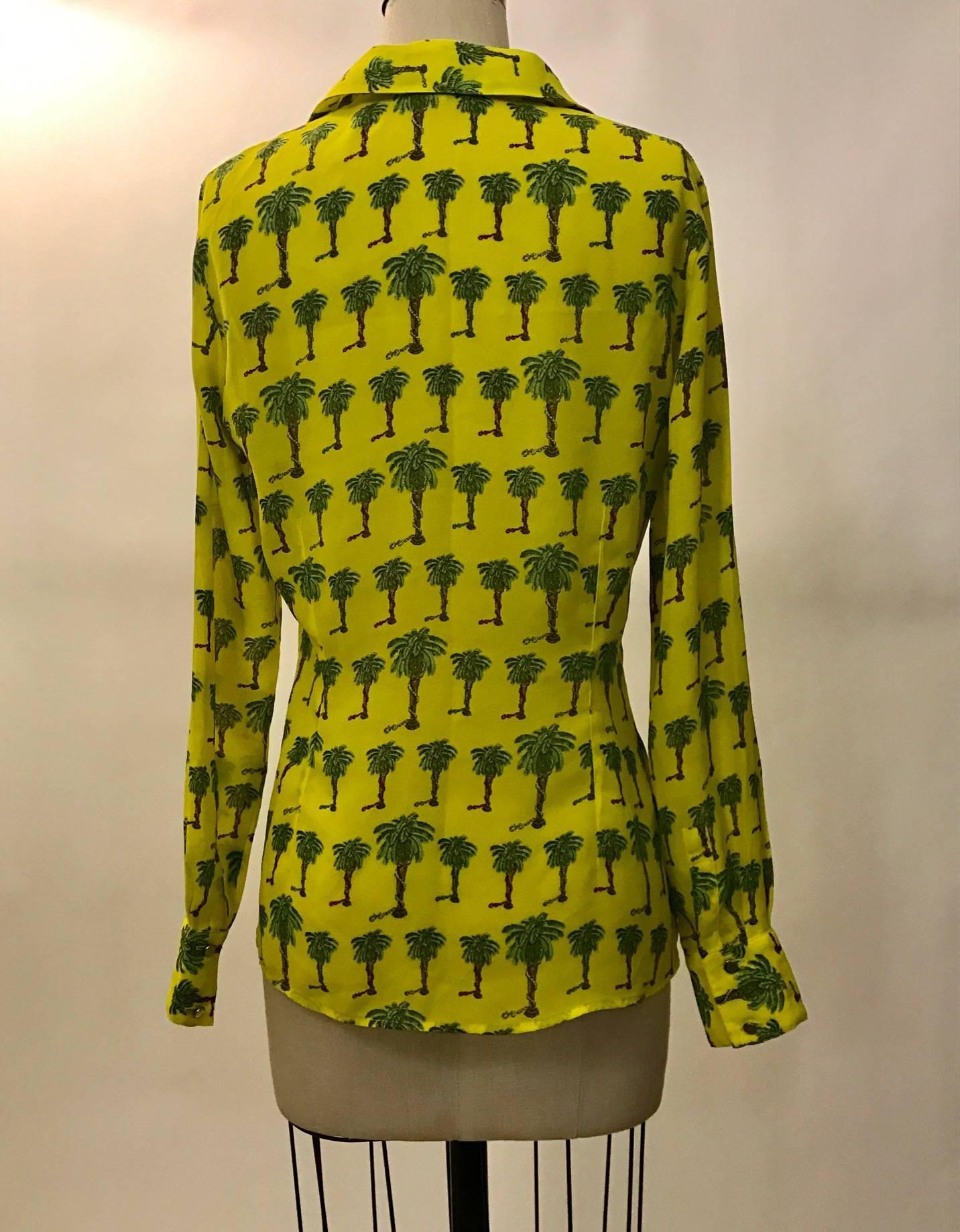 Versace Jeans Couture 1990s semi-sheer yellow collared shirt with palm tree print. Happy snakes in various colors climb the trunks of each tree. Patch pockets at each side of chest. Silver Versace medusa head logo buttons at front.

Made in