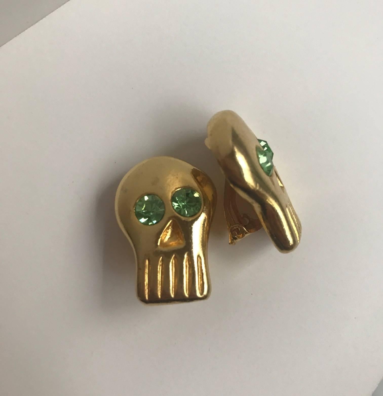 BillyBoy* Surreal Bijoux 1989 goldfarbene Totenkopf-Ohrringe mit grünen Kristallaugen. Jedes Stück von BillyBoy*s Modeschmuck wurde individuell angefertigt, und diese sind ein wunderbares Beispiel für seine kreative Arbeit! 

Ungefähr 1 1/8