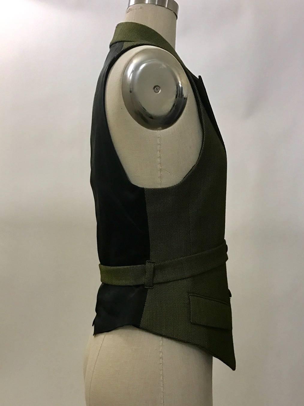 Alexander McQueen military inspired waistcoat vest in a yellow-green and black woven fabric with black satin back and collar. Attached belt wraps around the body and fastens at front buttons.  

Seen in the Fall 2001 What a Merry Go Round