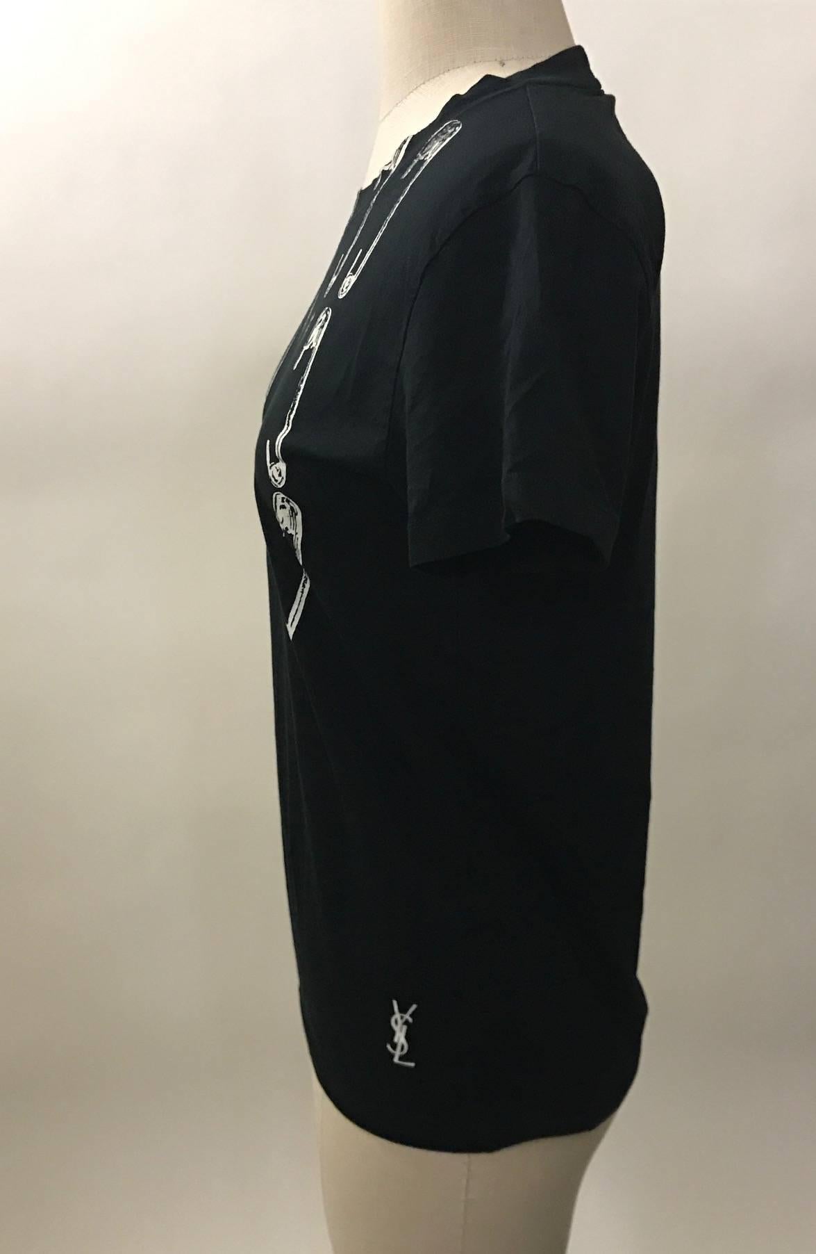 Yves Saint Laurent short sleeve black t-shirt with white screen printed safety pins and YSL logo at bottom side. Crew neck.

100% cotton.

Made in Italy.

Size IT 38, best fits XS. Light stretch, measurements taken unstretched.
Bust 33