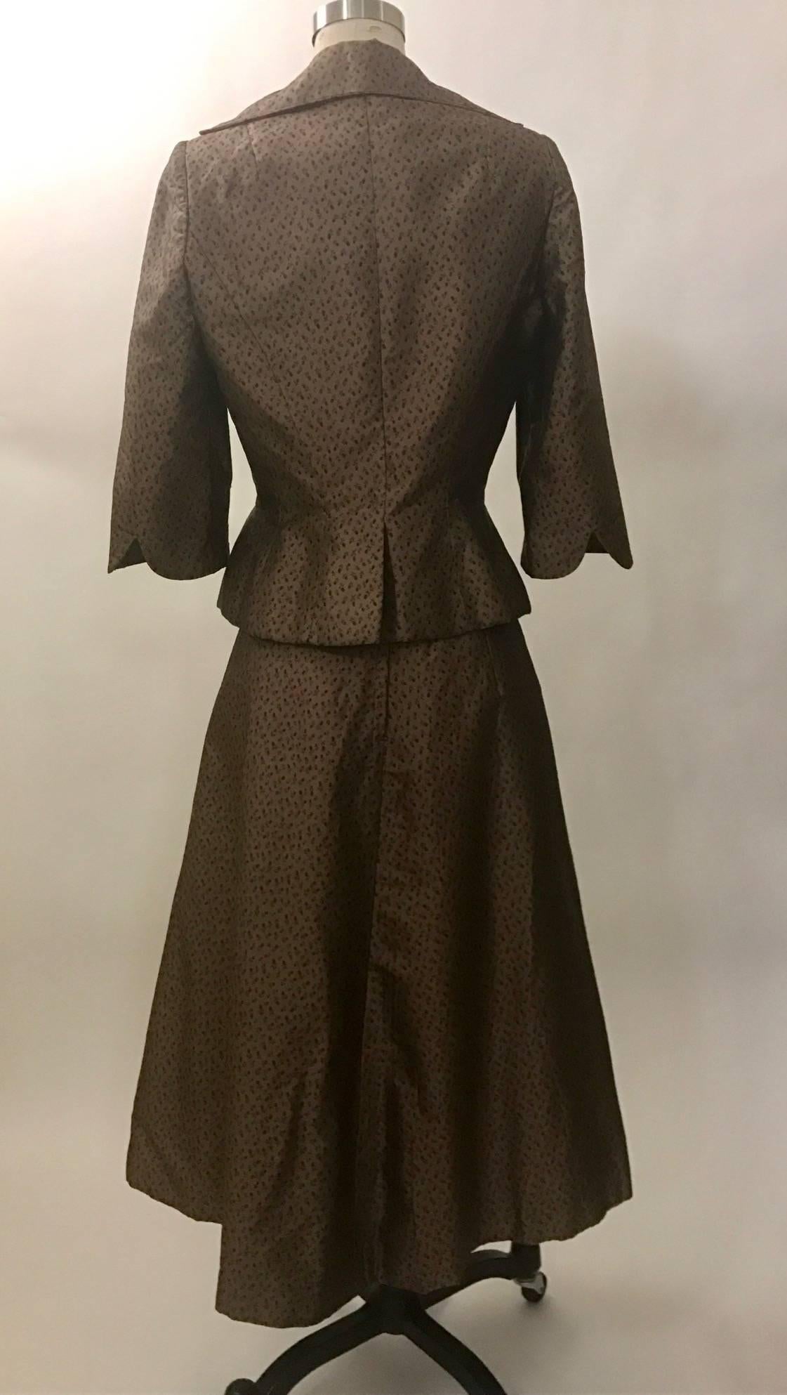 Brown ditsy floral print skirt suit designed by Jean Desses and produced in the U.S. by I.M. Bagedonow. Approximate circa 1953. Jelly bean shaped buttons at front jacket, skirt fastens at back with a zip and hook and eye.

The Metropolitan Museum of