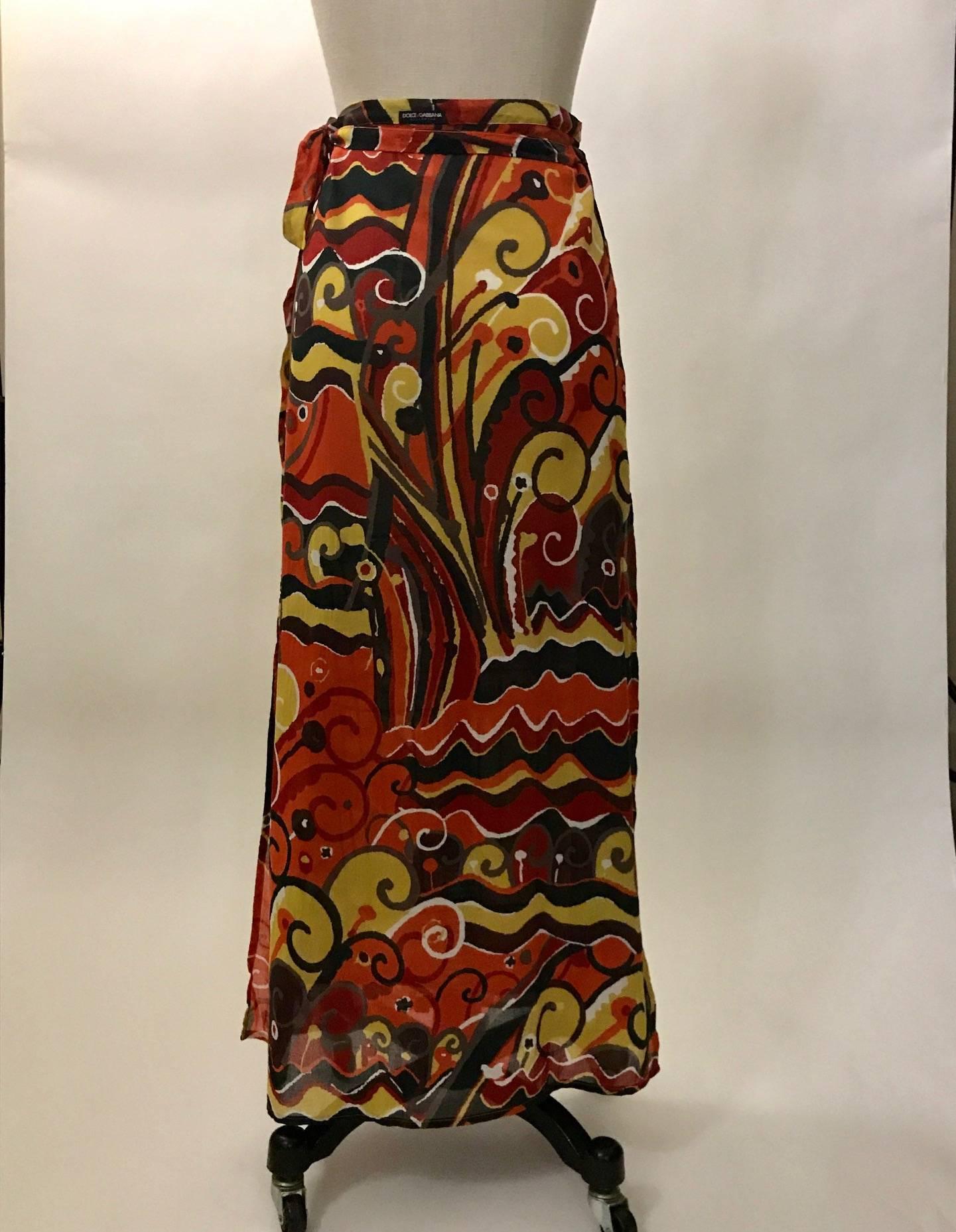 Dolce & Gabbana Beachwear orange wrap skirt with a batik like pattern throughout. Side slits, wrap ties at top. Small black Dolce & Gabbana beachwear label at exterior back. 

100% cotton.

Made in Italy.

Labelled size IT 1, US P.