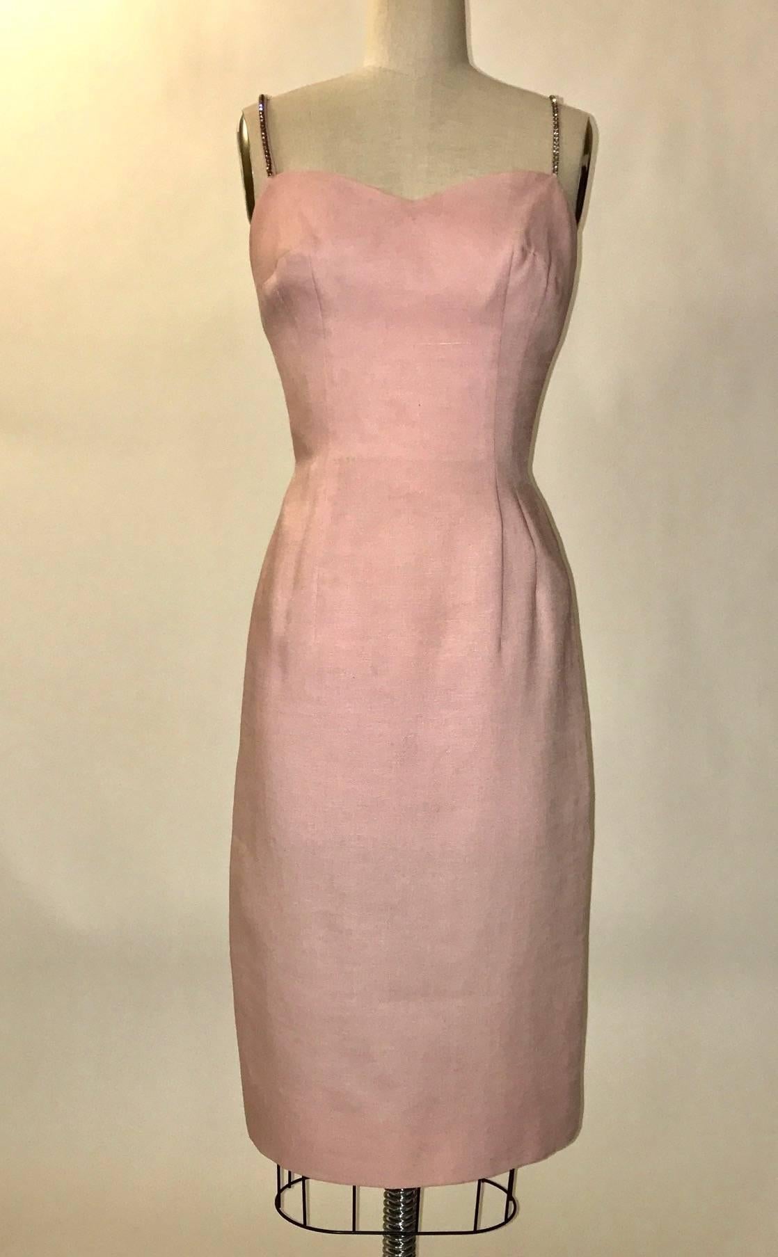 Mr. Blackwell blush pink linen wiggle dress from the late 50s or early 60s with rhinestone embellished straps. Fishtail skirt back with two more layers of cascading fabric falling at back. Back zip, bow at top with snap fastener. 

Lined at top.