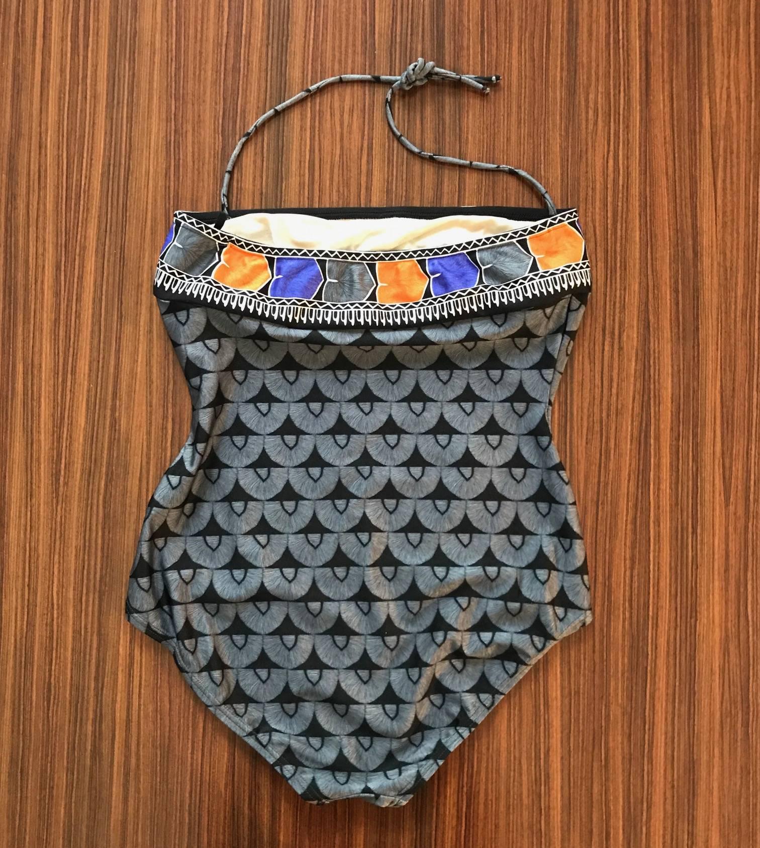 Yves Saint Laurent 1980s swimming suit with a grey and black pattern throughout and orange and blue pattern trim at top. Two strings at top tie in halter style around the neck. Lined at bust and bottom. 

80% nylon, 20% spandex.

Designed in France,