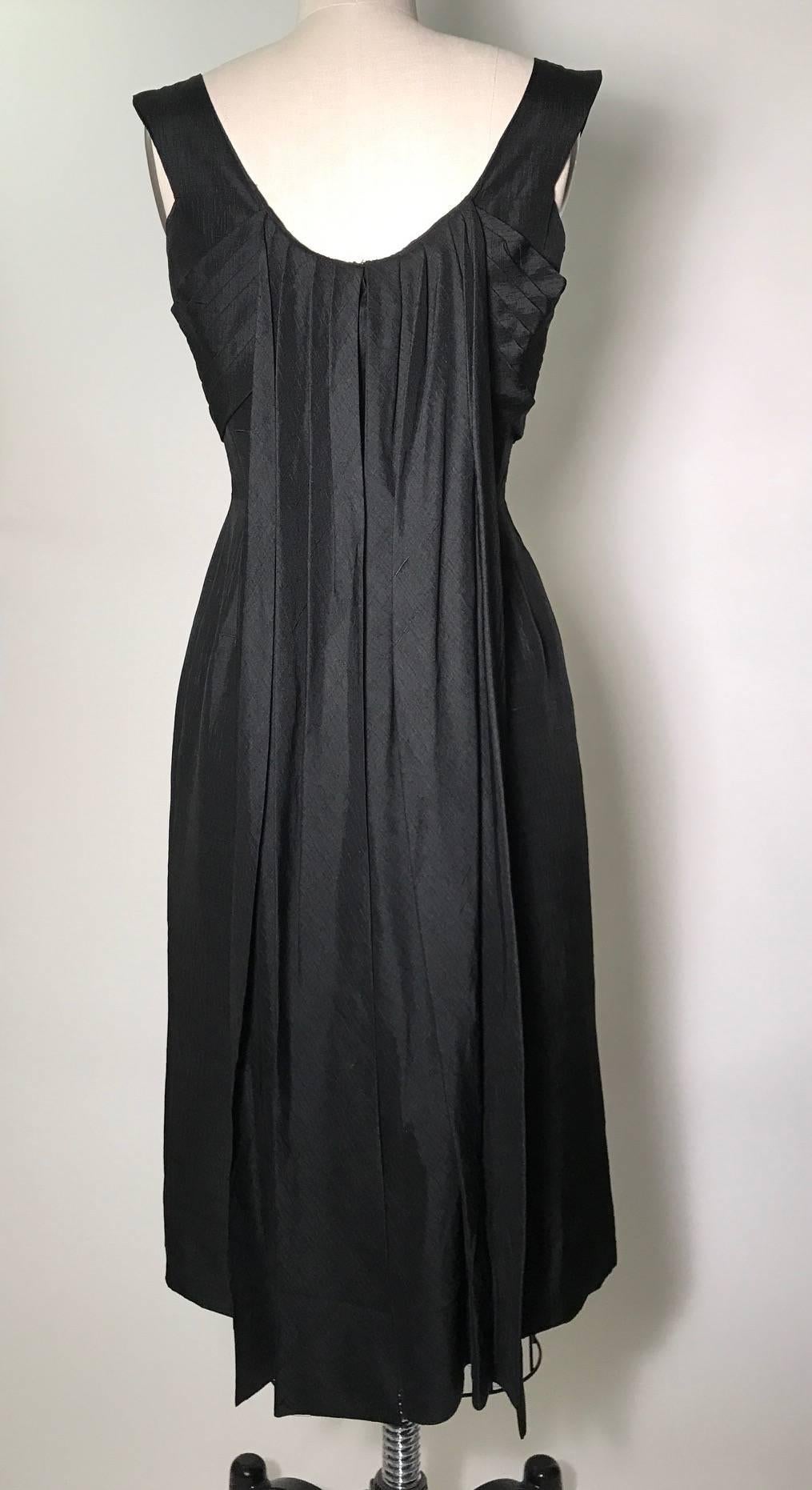 Suzy Perette 1960s little black dress with pleated bow detail at front bodice and draped panels at back. Metal zipper and hook and eye at back. 

No content label, seems like dupioni silk.

No size label. Seems to best fit an XS or 2, see