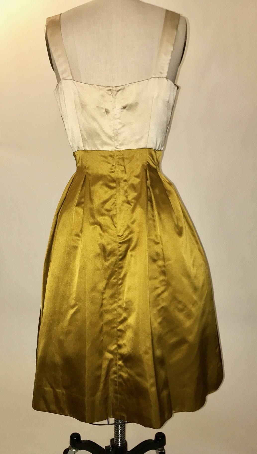 Jean Marchand for Friedlander vintage 1950's silk satin dress with pleated bodice and sweatheart neckline. Beaded trim at neckline and ends of ivory drape detail at skirt. Inverted pleating at waist and mesh tulle underlayer create volume at full