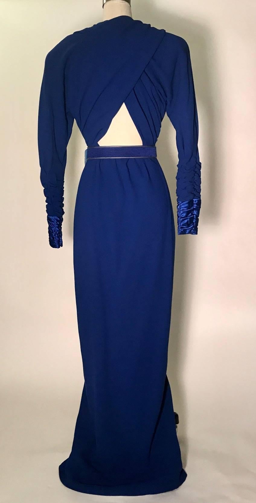 Bright blue James Galanos 1984 crepe gown from the costume collection of the Metropolitan Museum of Art. A stunning full length gown with plunging front, criss cross peekaboo back, and high center front slit. Long and full zippered sleeves are