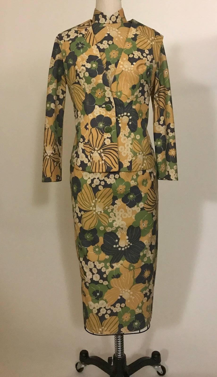 Long sleeve floral print cheongsam dress with matching vest in muted tones of gold, green, navy and cream. Estimated decade 1960s, but may be more recent. Dress has side zip with hidden snaps at chest and hook and eye at neck. Vest fastens with two