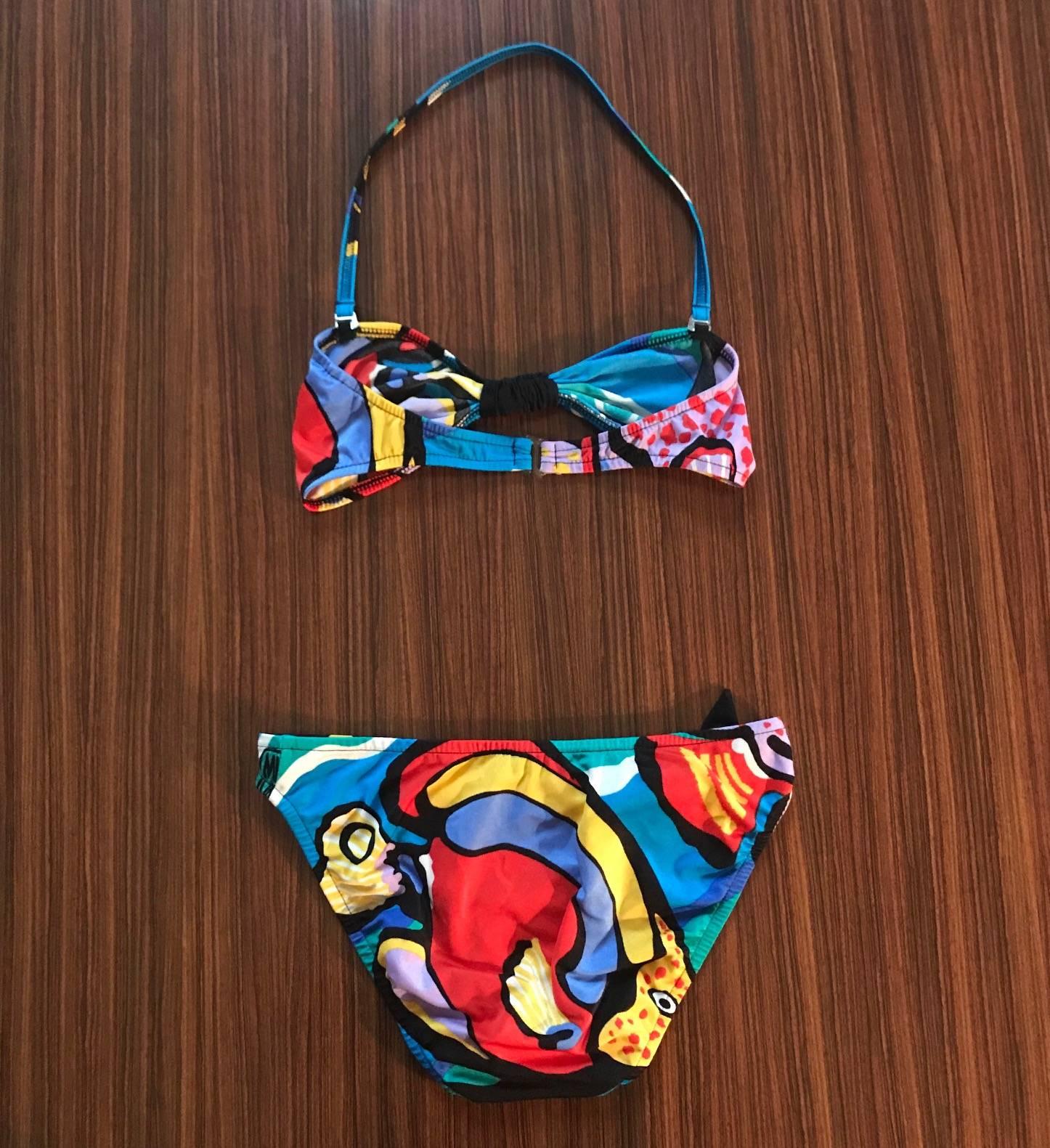 Michaele Vollbracht for Sofere 1980s bikini bathing suit in a colorful abstract pattern. Unlined bandeau top with removable halter strap, bikini bottom. Half-bow adornments at chest and hip.

85% nylon, 15% lycra.

Made in USA.

Labelled size 10,