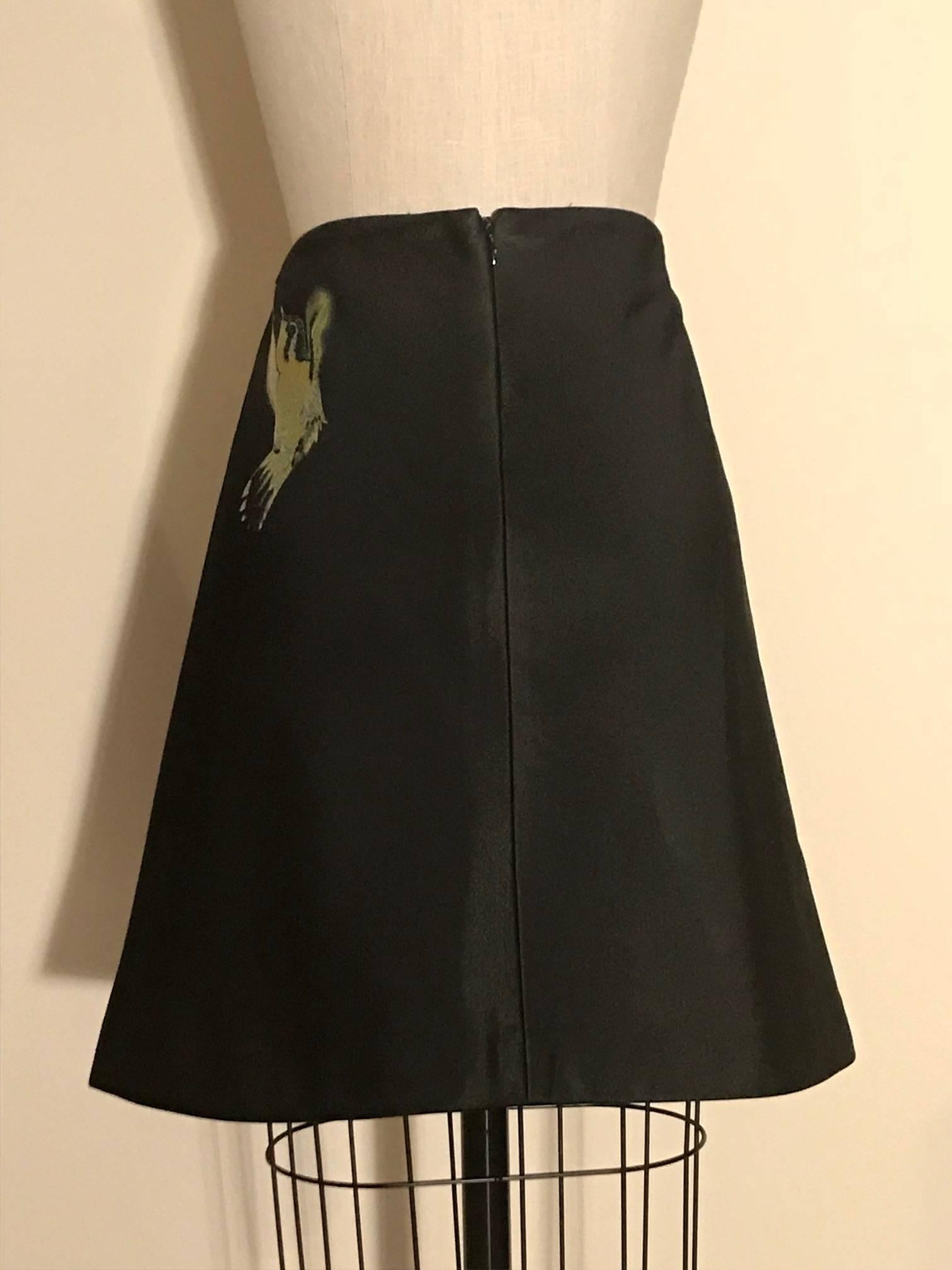 Alexander McQueen black A-line skirt featuring a hummingbird and smoke like wisp pattern. Overlapping slit at center front. Back zip and hook and eye.

Judging by the large format tag, we think this piece may be a production sample.

No content