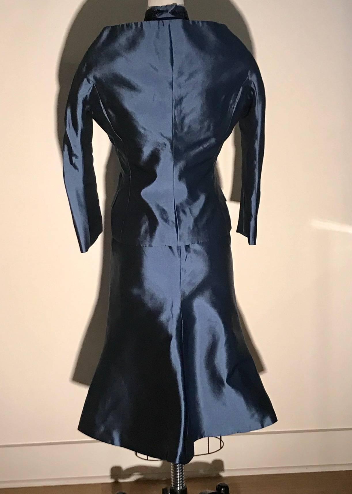 Alexander McQueen blue suit with amazing double collar detail, featuring black fern like beading at collar as well as skirt waist. Jacket fastens with small black cloth covered buttons, skirt zips at center back. 

100% silk.
Fully lined in 100%