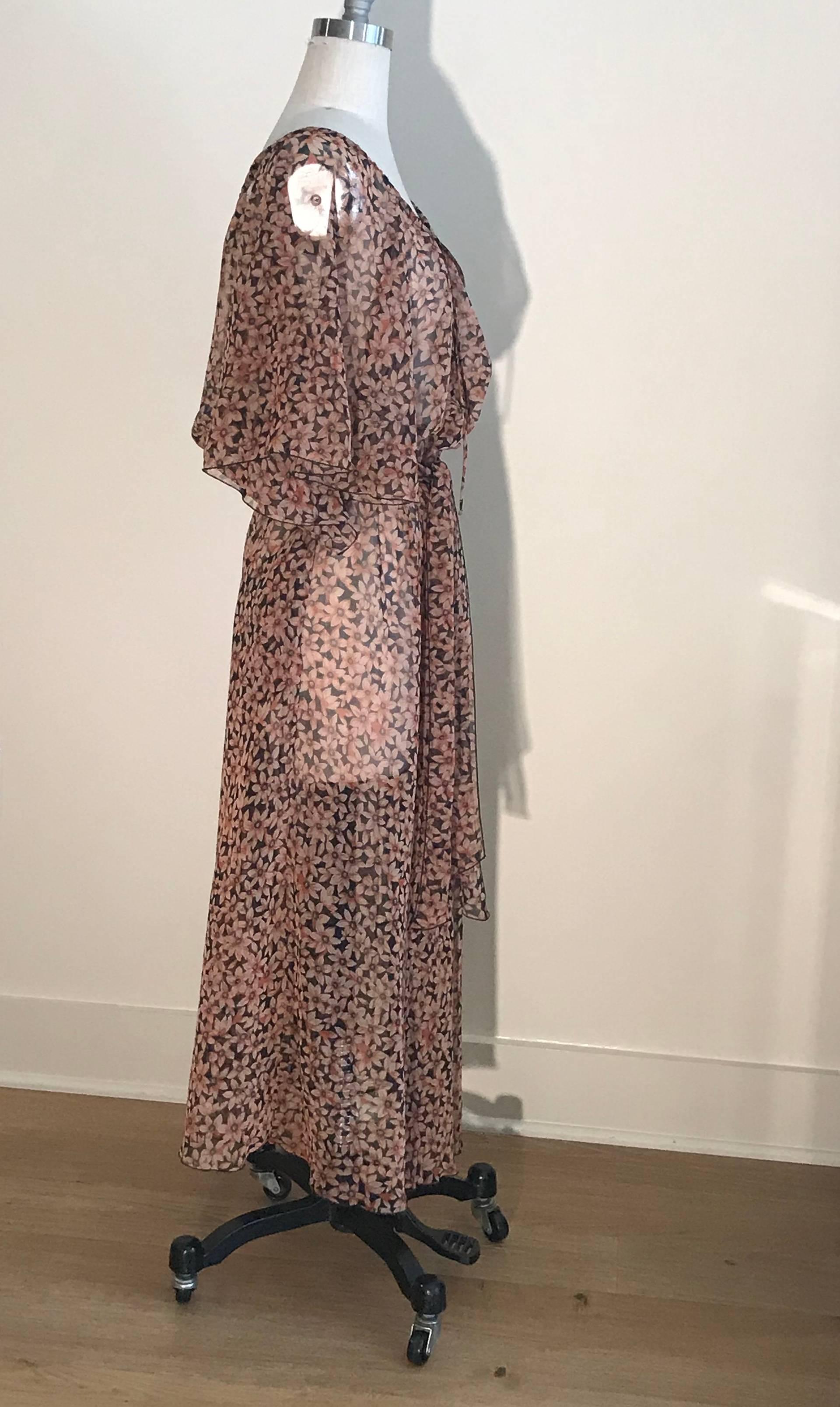 Vestido vintage Diane von Furstenberg de los años 80 con cinturón ligeramente transparente y estampado floral negro y rosa. Botones forrados de tela en la parte delantera central. Lazo al cuello. Mangas de volante. 

Es ideal para cubrirte en la