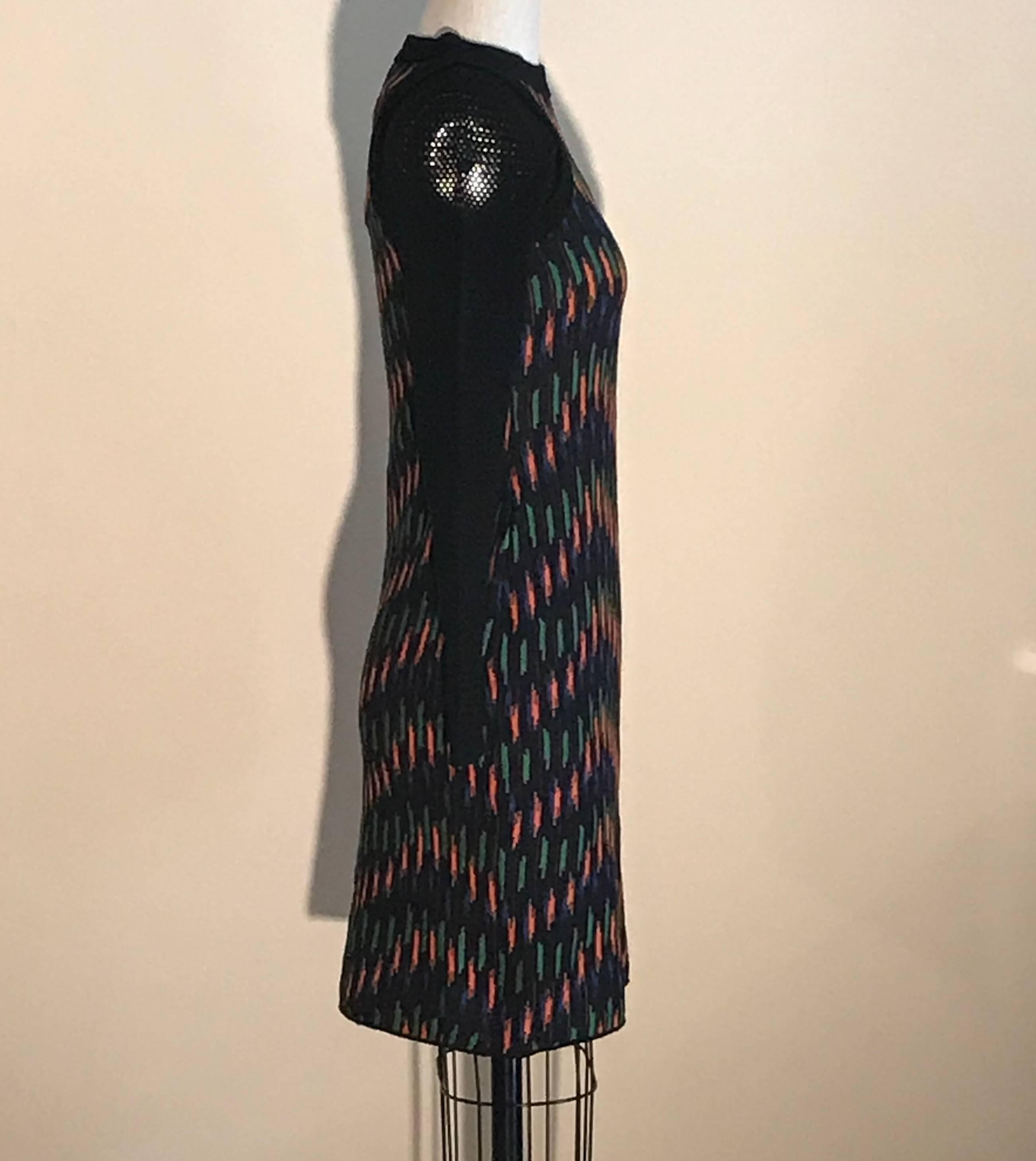 Vestido de punto negro de M Missoni con estampado naranja, verde y azul. Los hombros y las mangas de malla negra asoman desde un corpiño de punto. 

Tejido 1: 56% algodón, 20% viscosa, 14% poliamida, 10% lana.
Tejido 2: 46% viscosa, 22% poliéster,