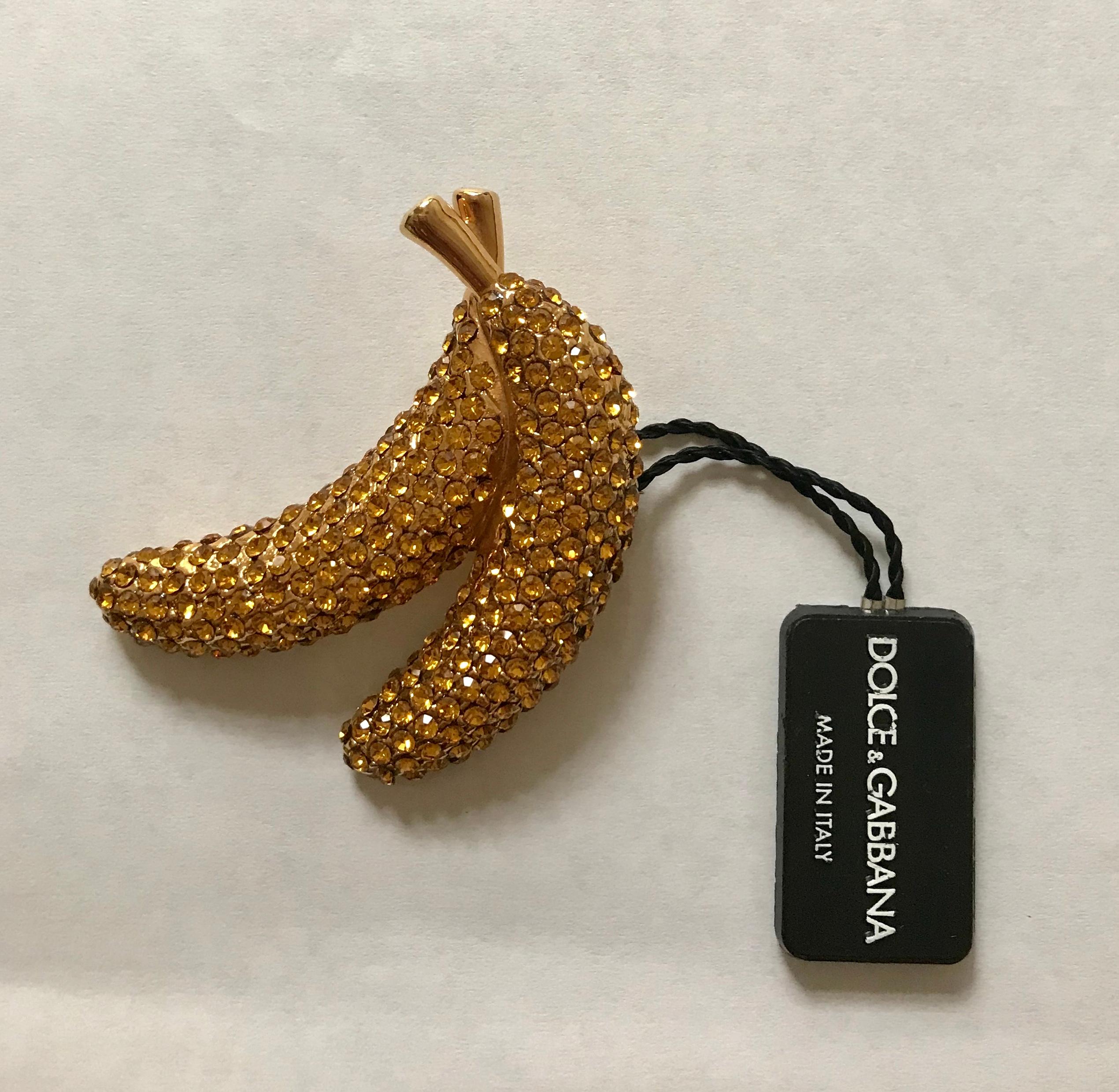 Dolce and Gabbana gold tone Frutti Banana Brooch featuring two bananas covered in dazzling yellow crystals. Signed 'Dolce and Gabbana' at back. 

Includes box and authenticity card.

Crystal/Brass.

Approximately 2.5