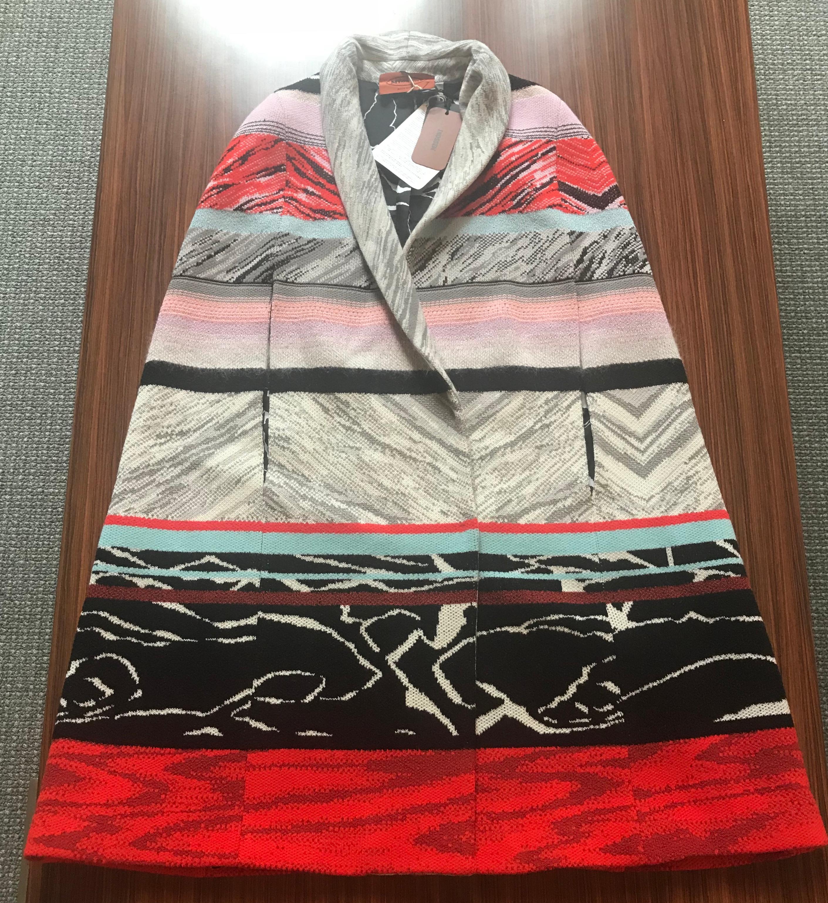 Missoni (mainline)  knit cape in red, black, white, grey and pastel pattern stripe knit. Shawl Collar. Slits at front sides for arms. Black and white patterned lining. Fastens at front with three hidden snaps. Extra snaps included. 

81% wool, 11%