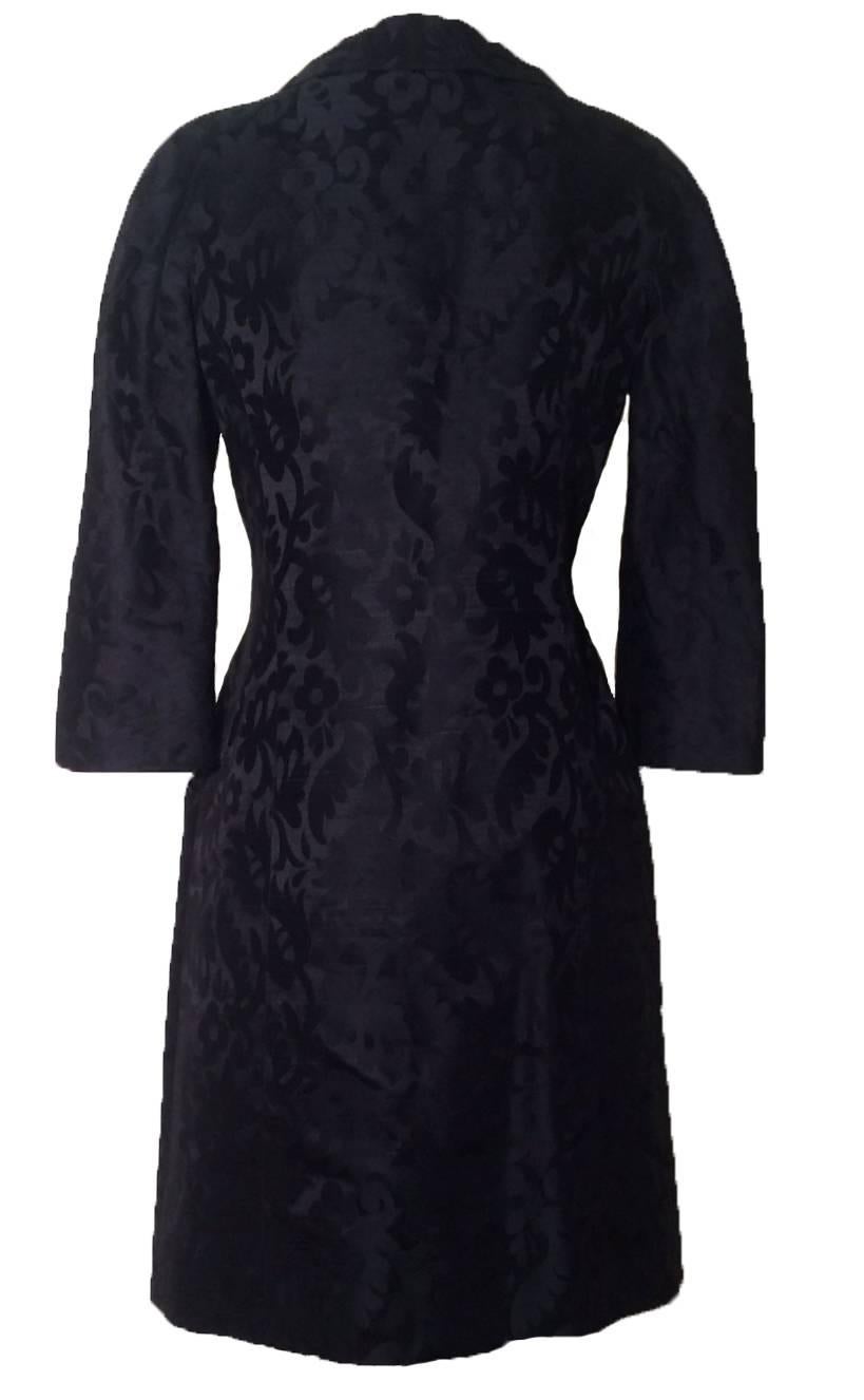 Hattie Carnegie late 1950s or early 1960s black coat dress in a stunning floral silk jacquard. 

Two front pockets. Fastens with silk covered  buttons from waist up to peter pan collar. Mid length sleeves. 

No size tag. Fits like a Large, see