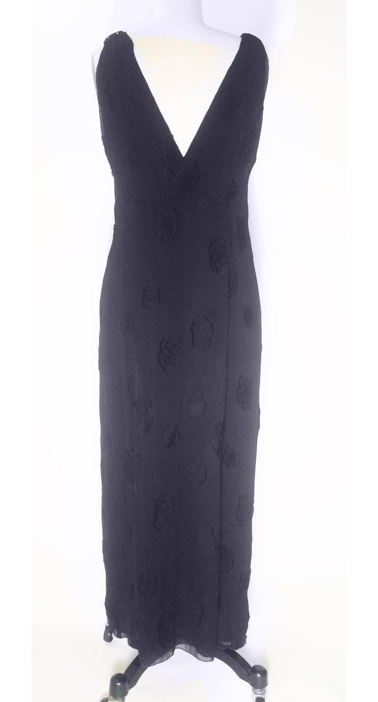 Chanel black maxi dress with Chanel's signature camellia flowers appliqué throughout. Sheer crinkle-pleated overlay over solid black lining with V neck at front and back. Metal CC logo on a camellia at hip, side zip. 

74% rayon, 25% silk.
Lined