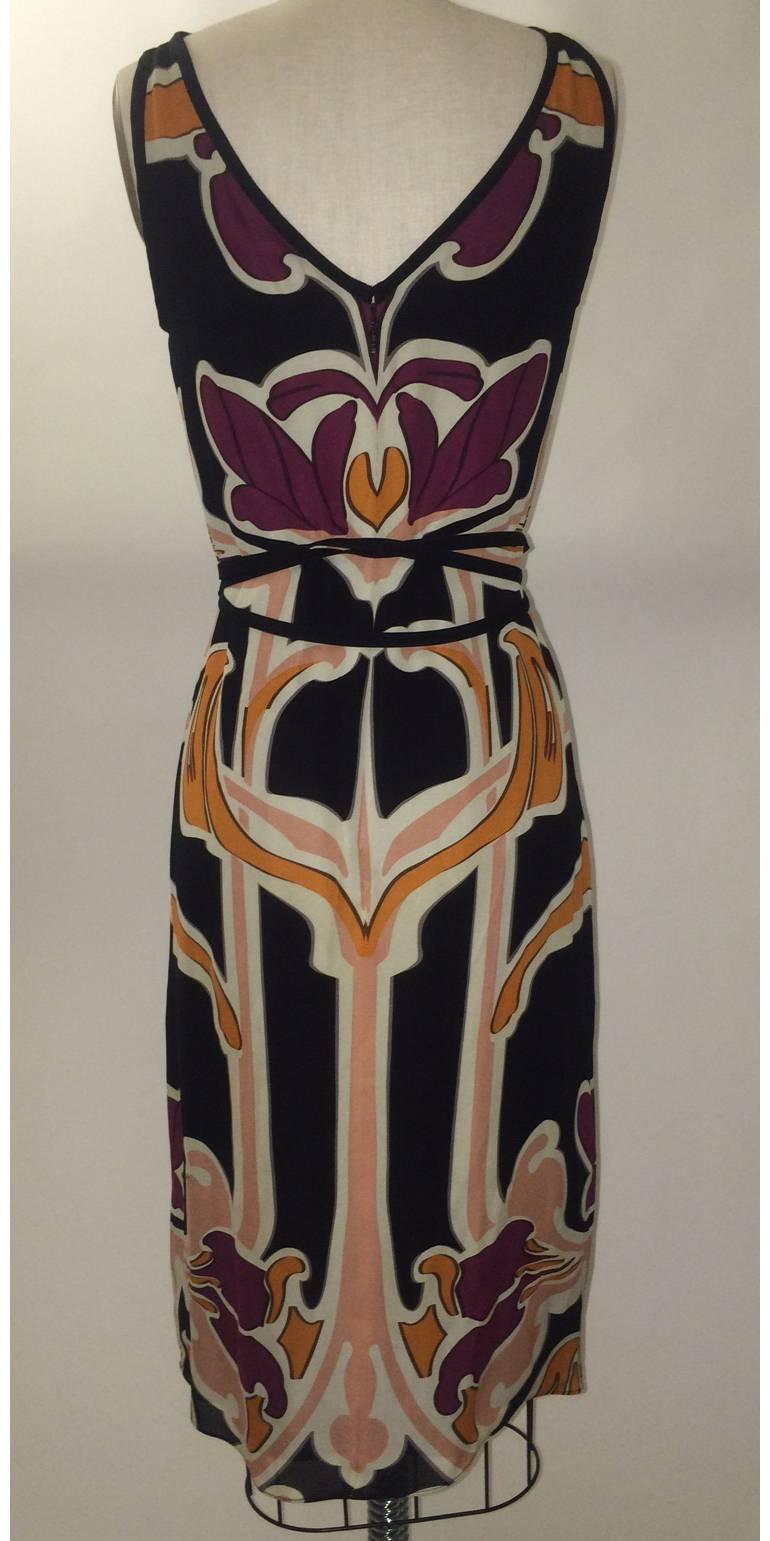Gucci Spring 2014 black silk dress in plum, peach, orange, and cream Art Nouveau florals inspired by Erte prints. Black underlay, long belt to criss-cross at waist. Bateau neck at front descends into a v at back. Back zip. 

Made in Italy.

Size