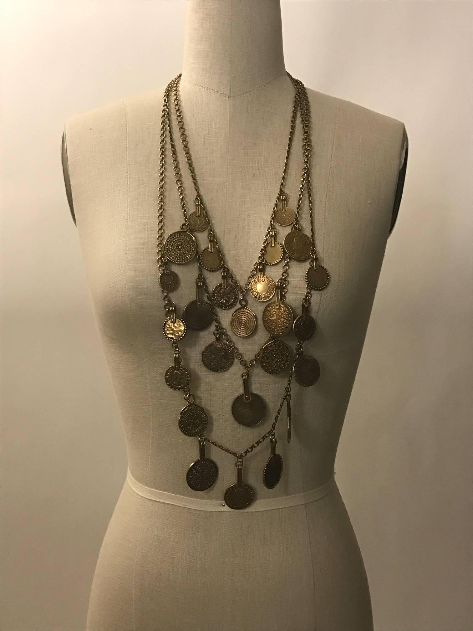 Vintage gold tone tone Yves Saint Laurent triple-strand medallion charm necklace from his 1977 gypsy themed collection. Light patina. Signed YSL at S hook closure and hang tag.

Seen on Farrah Fawcett in Vogue. 

Very good condition, gently worn