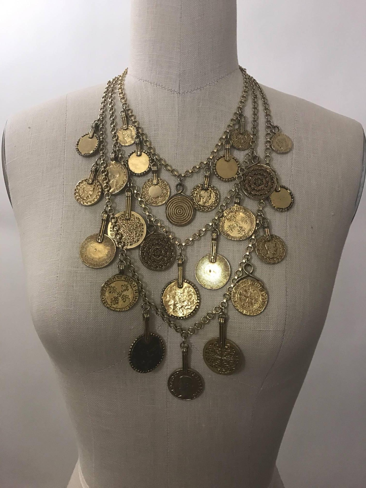 Vintage gold tone tone Yves Saint Laurent triple-strand medallion charm necklace from his 1977 gypsy themed collection. Signed YSL at S hook closure and hang tag.  

Seen on Farrah Fawcett in Vogue.   

Very good condition, some light wear to finish