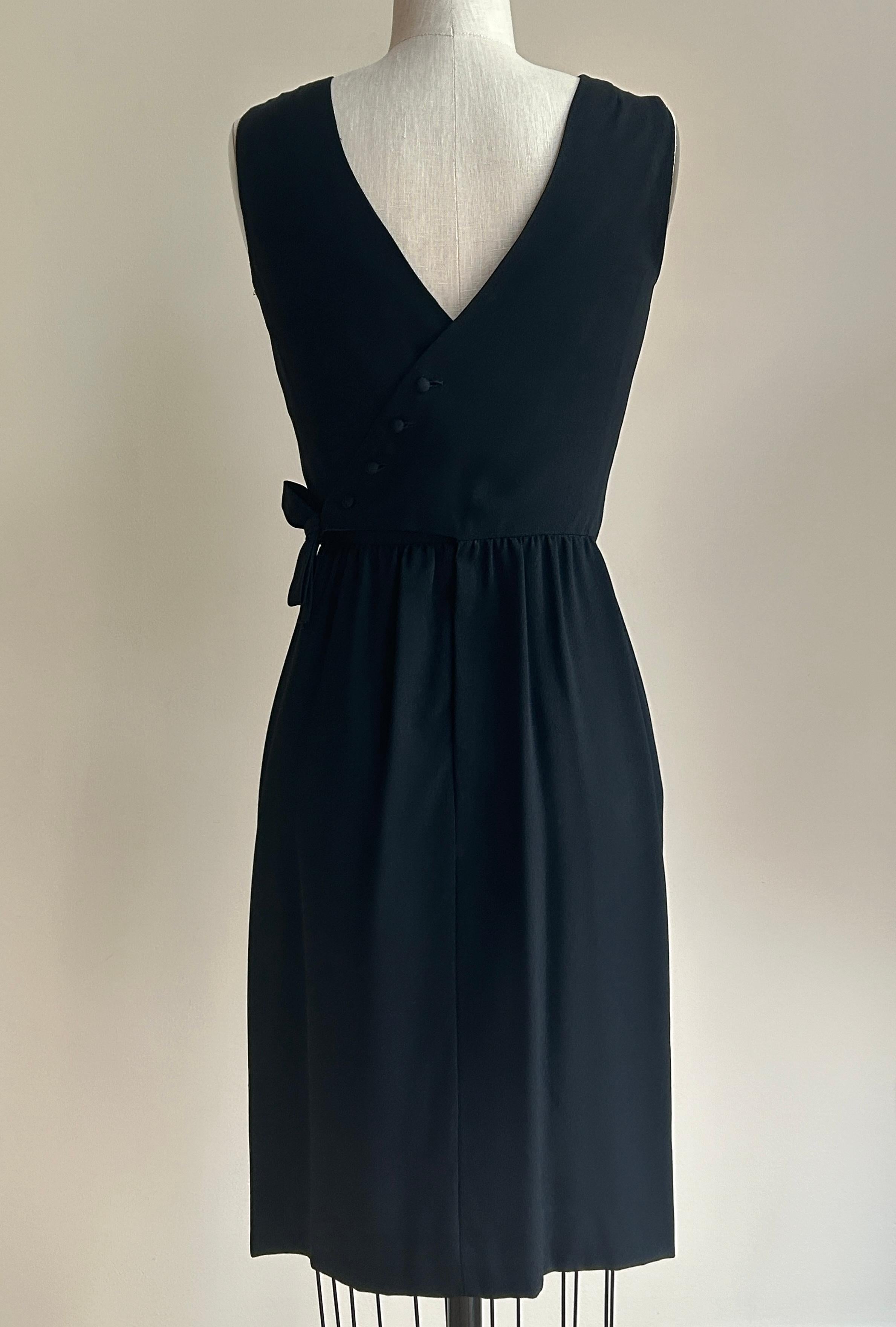 Vintage 1960s little black dress by Lanz Originals for Bullock's of Wilshire Collegienne department.  Crossover wrap detail at back. fastens with snaps, hook and eye, and four cloth covered buttons. Bow at side-back snaps in place. Light gathering