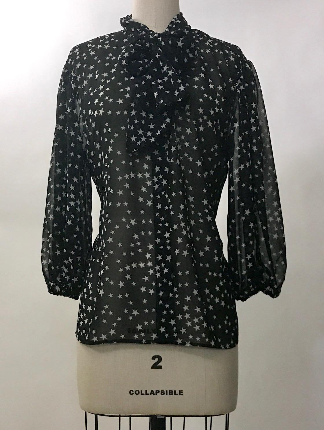 Dolce & Gabbana semi-sheer black and white star print blouse from the Fall 2011 collection. Fabric at neck can be tied as a pussycat bow or left to hang for a scarf like look. Elastic at cuffs creates a slightly voluminous sleeve. Button