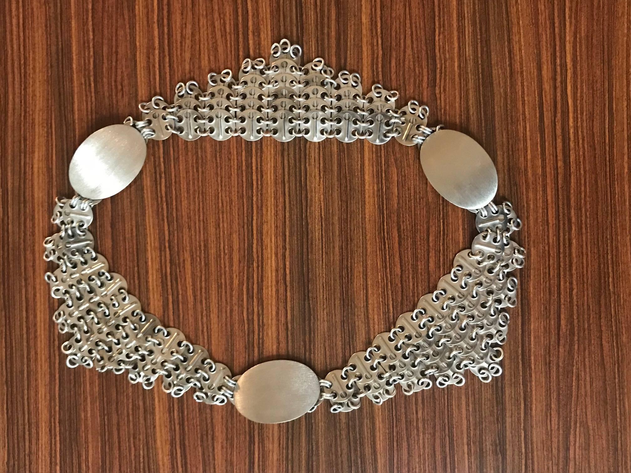 Paco Rabanne vintage silver belt featuring Rabanne's signature linked discs, assembled to hang in triangular shapes. Large brushed silver ovals connect the small discs. We also think it looks great draped across the shoulders as a necklace!

Fastens